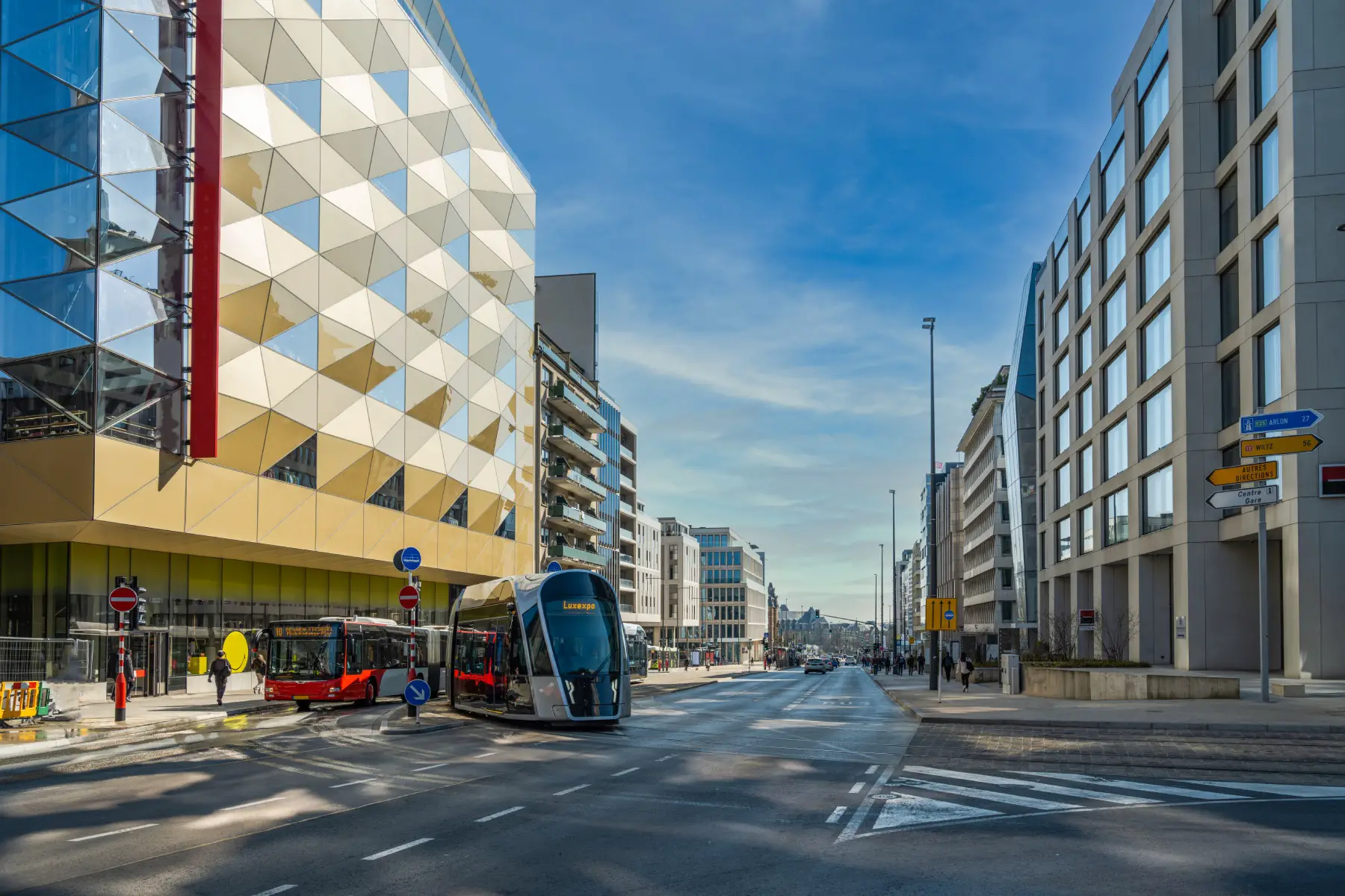 an electric tram crossing the road in Luxembourg City on a sunny day