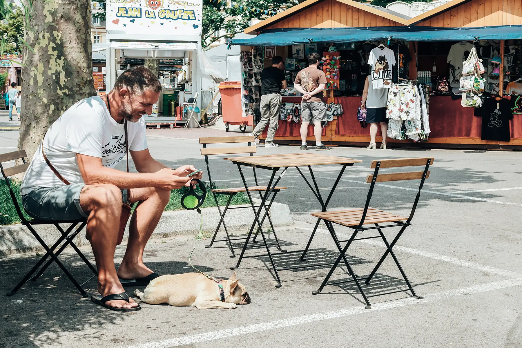 A warm summer day, a man sitting with his dog near market stalls in Luxembourg City