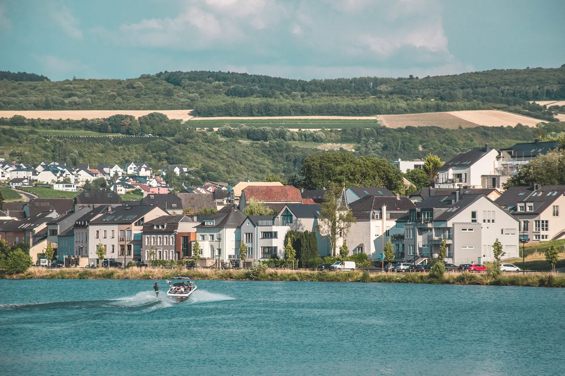 Houses on the waterfront of a lake, people in a speedboat in front