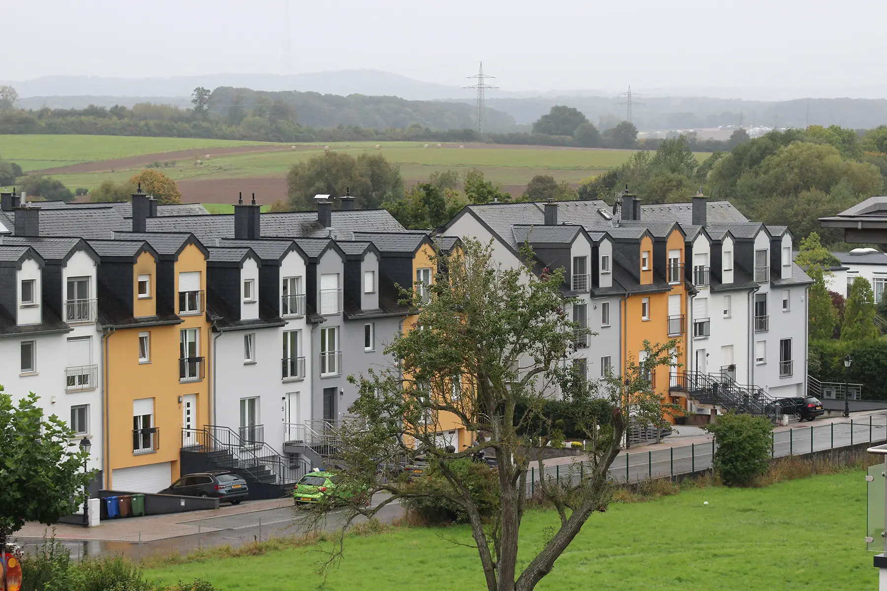 A row of white, grey, and yellow houses on a rainy day in Luxembourg
