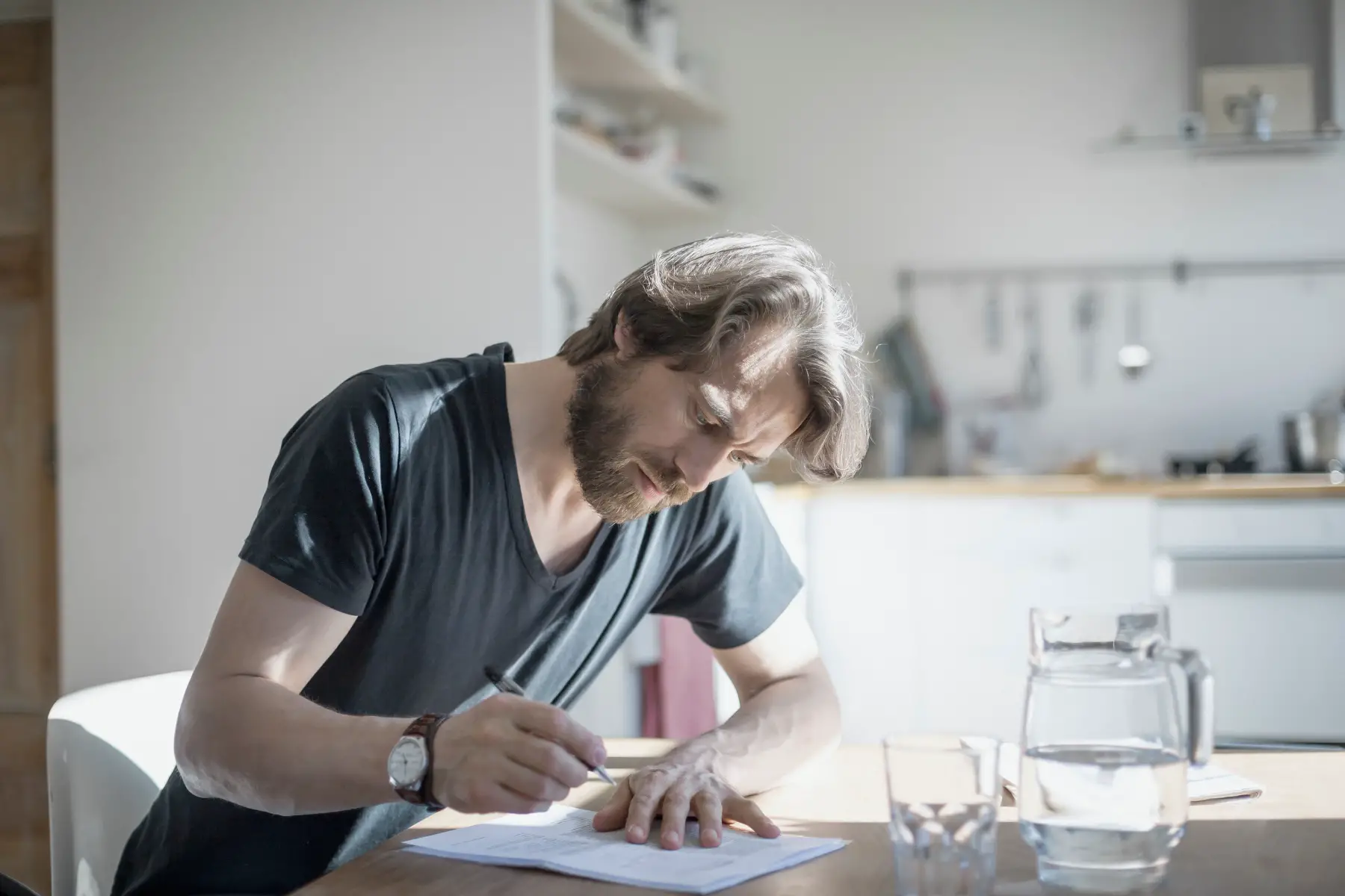a man sitting at a table in an apartment and signing a contract