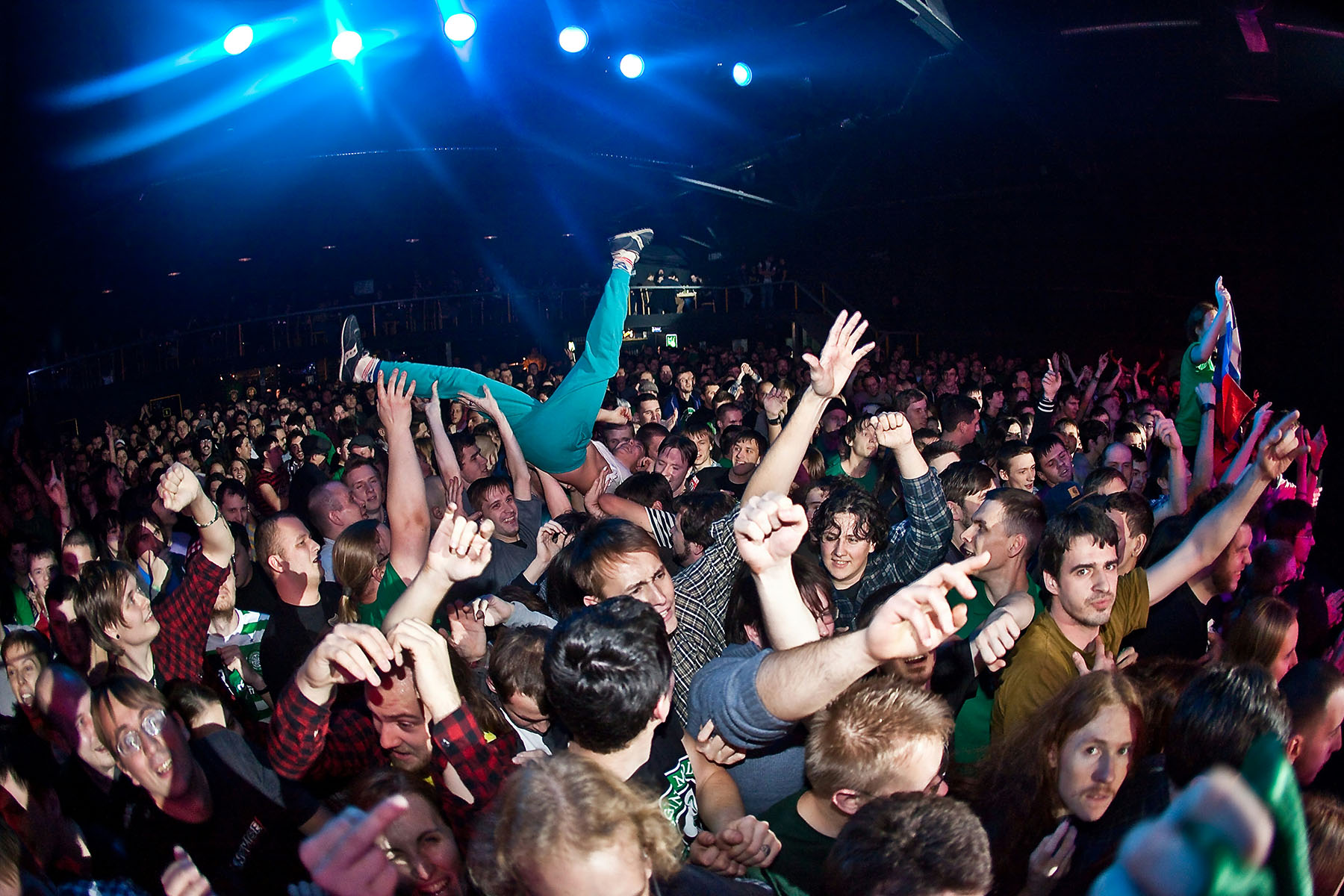 Artist does a stage dive into a large crowd of concert goers.