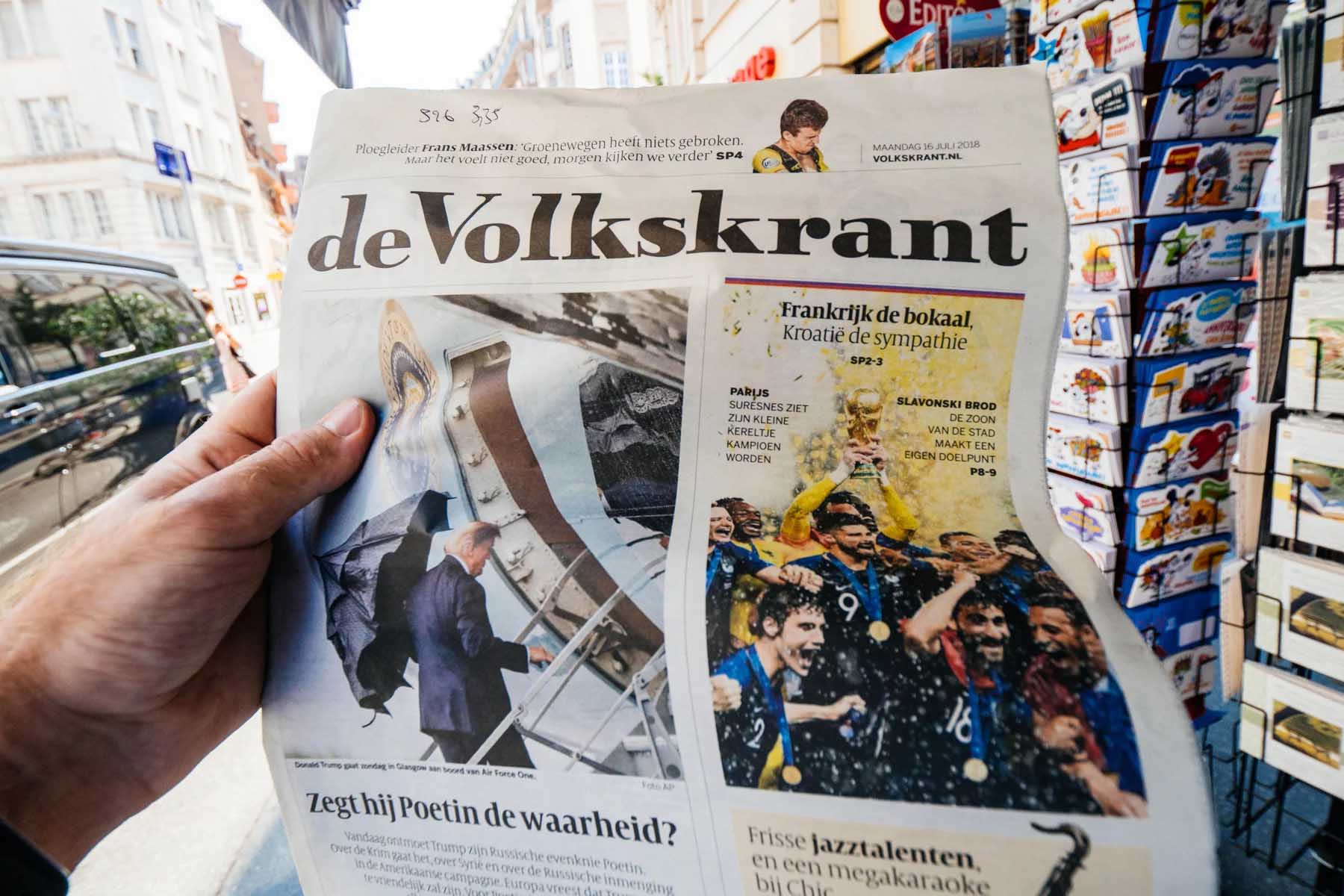 Someone holding a copy of the Dutch newspaper De Volkskrant.