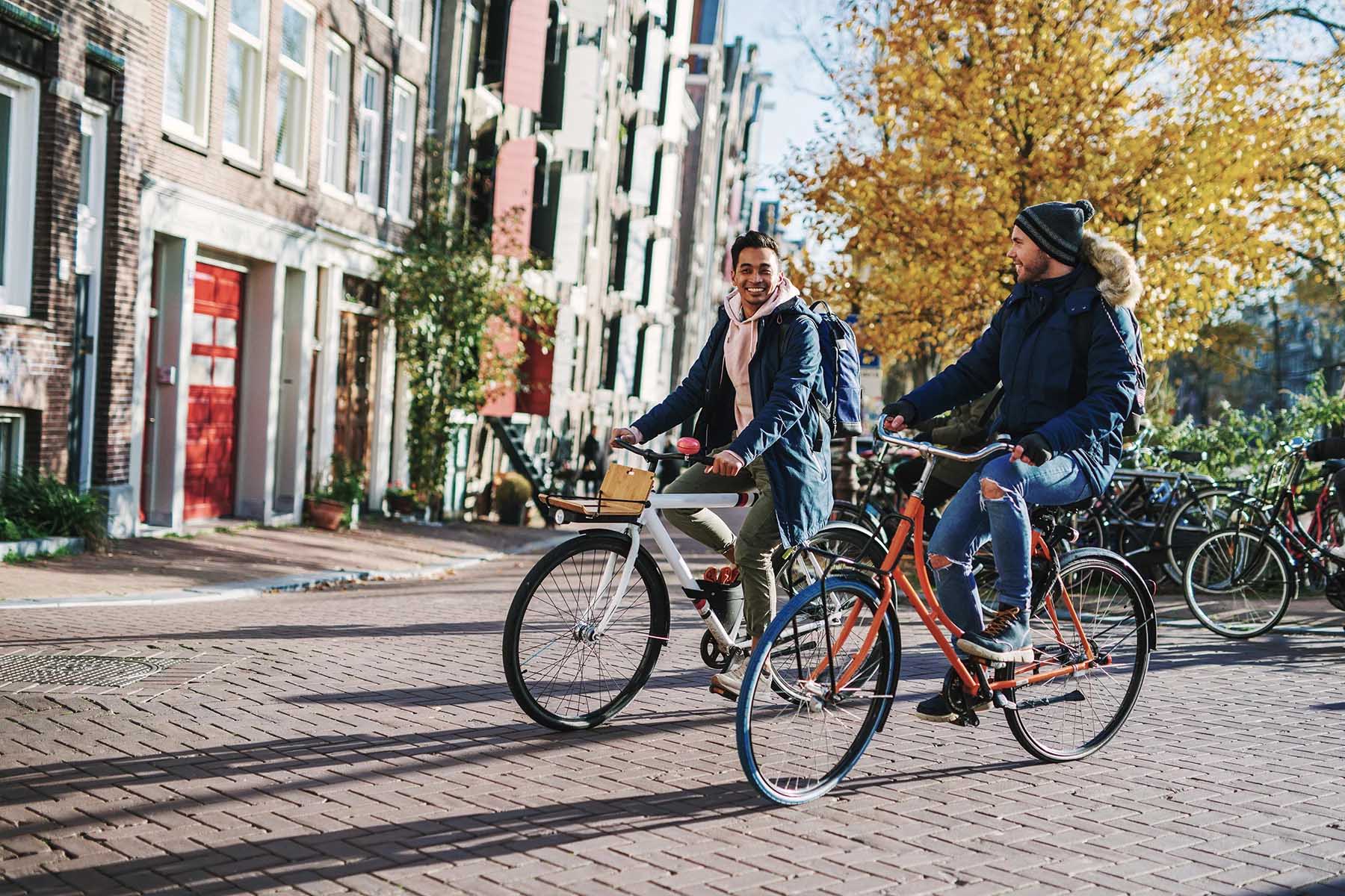 Cute couple smiling and cycling through Amsterdam on a sunny winter's day.