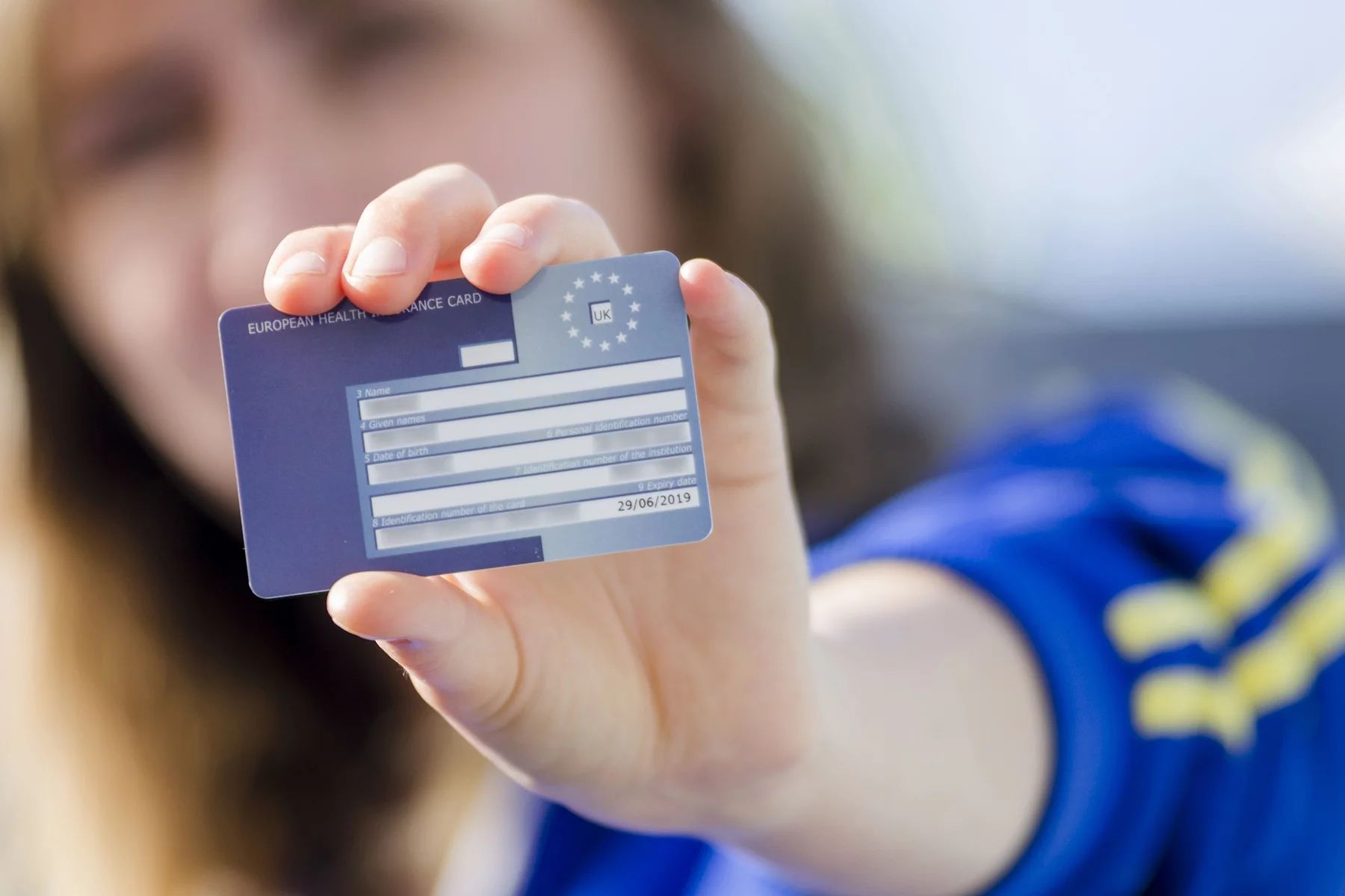 a woman holding up her European Union Health Insurance Card (EHIC) 