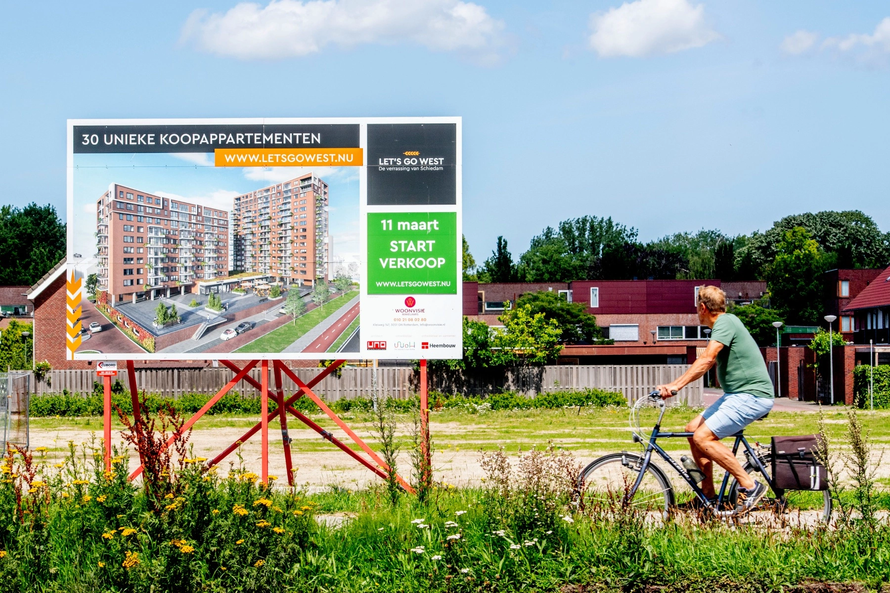 Man cycles past an board advertising apartments for sale in Schedam