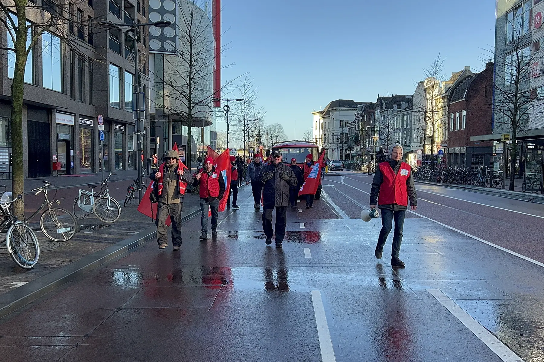 Striking workers in red jackets walking along a road