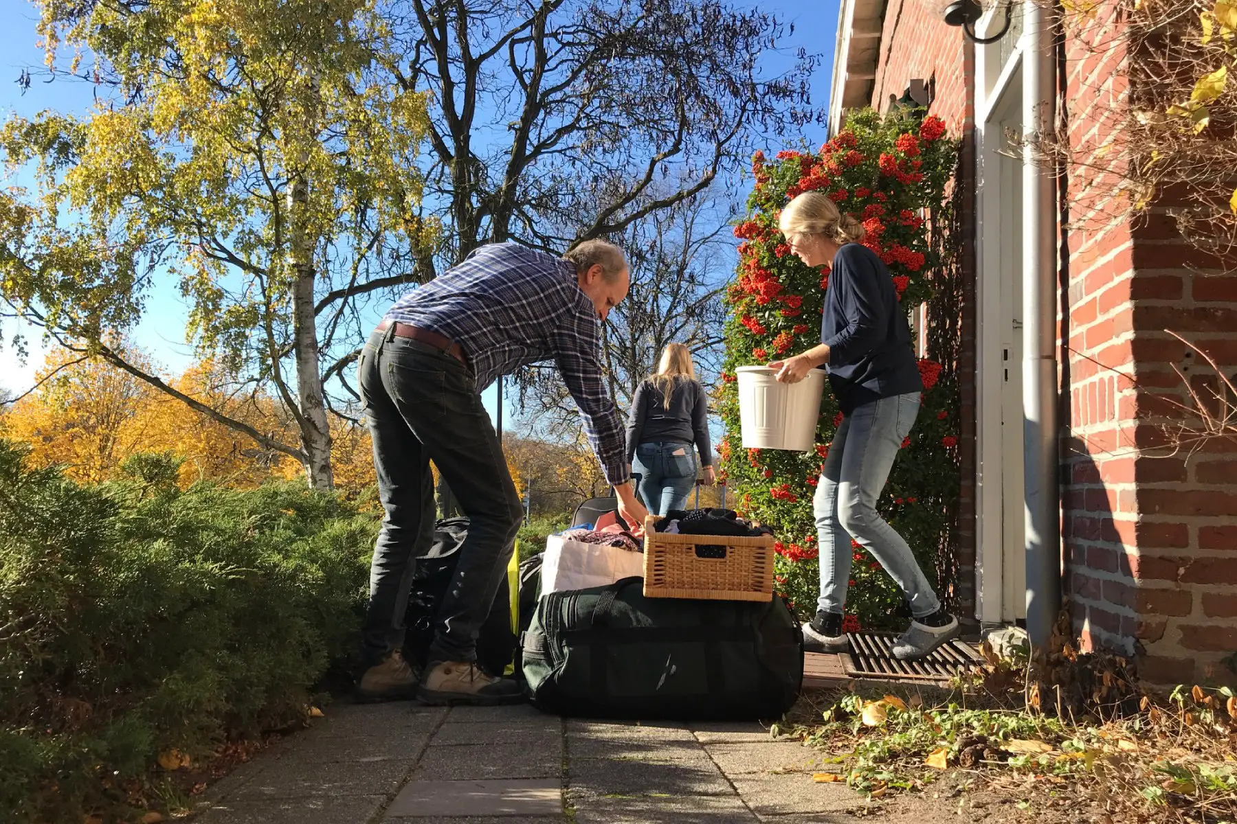 a family packing up moving boxes outside of a house with flowers and greenery in the background