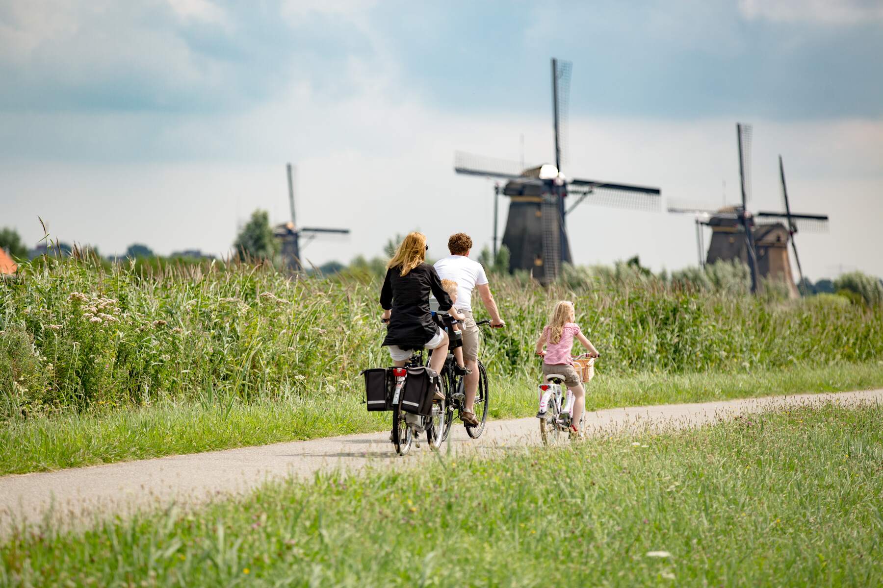 Family cycling next to windmills in Kinderdijk