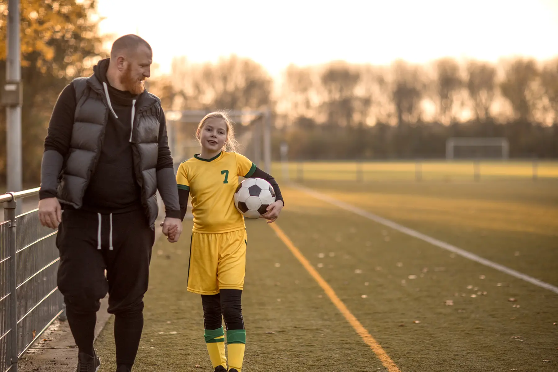 A father with his daughter in a football kit, Autumn day