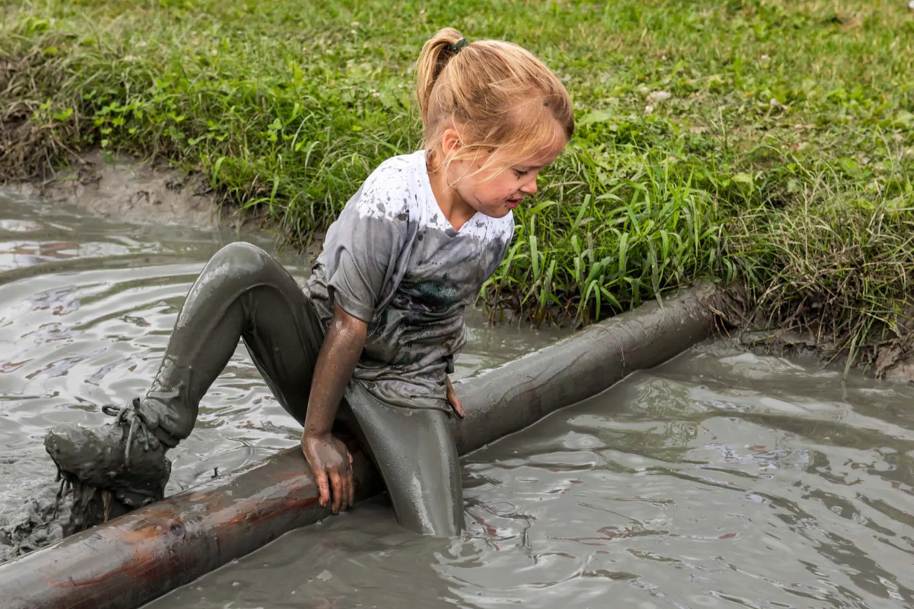 girl playing in muddy canal