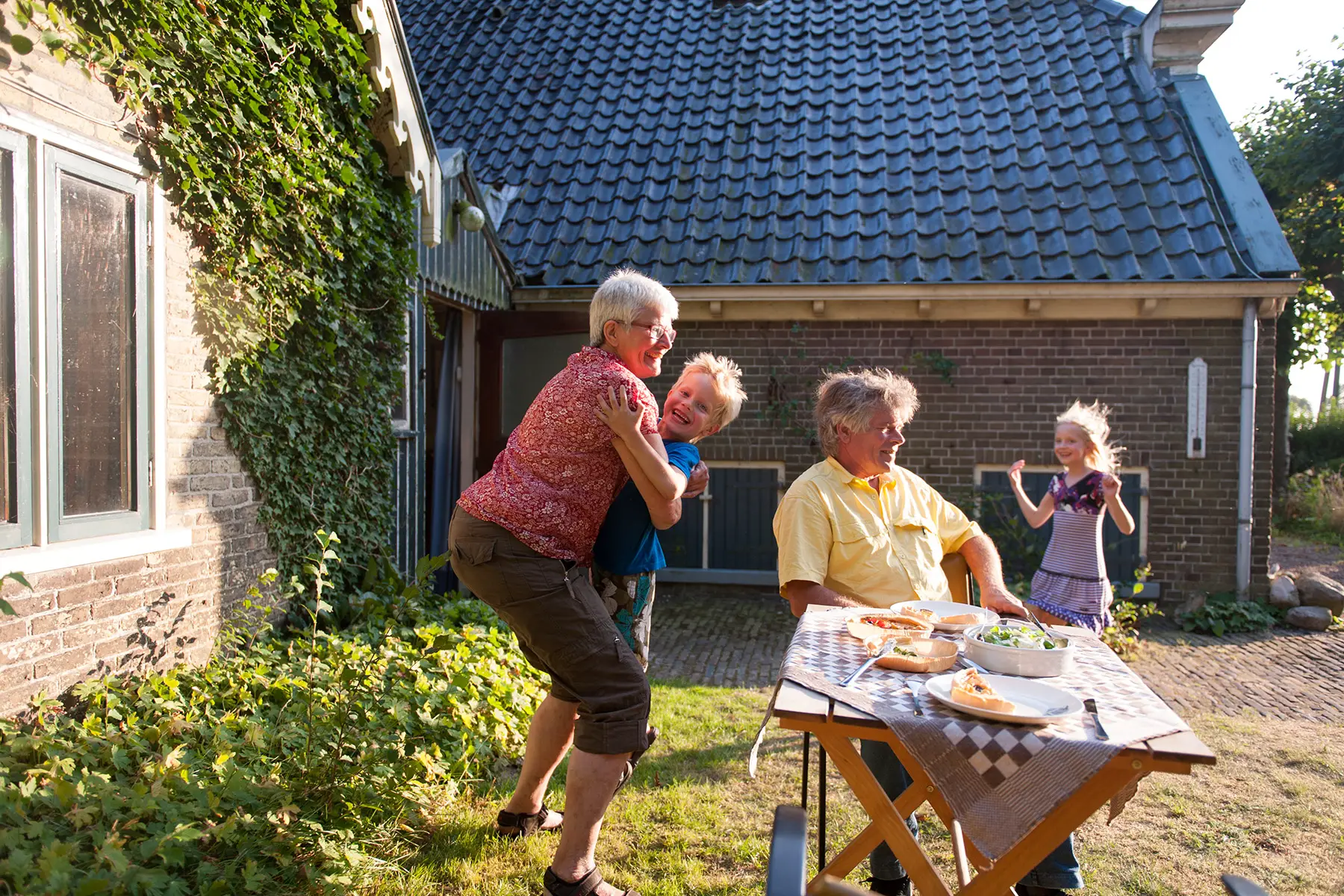 Grandparents hugging their grandchildren in a garden on a sunny evening