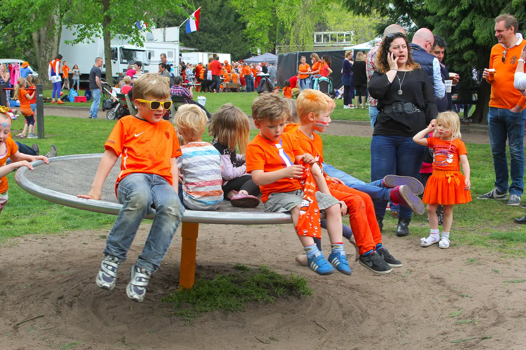 Kids on a roundabout in a play area on King's Day