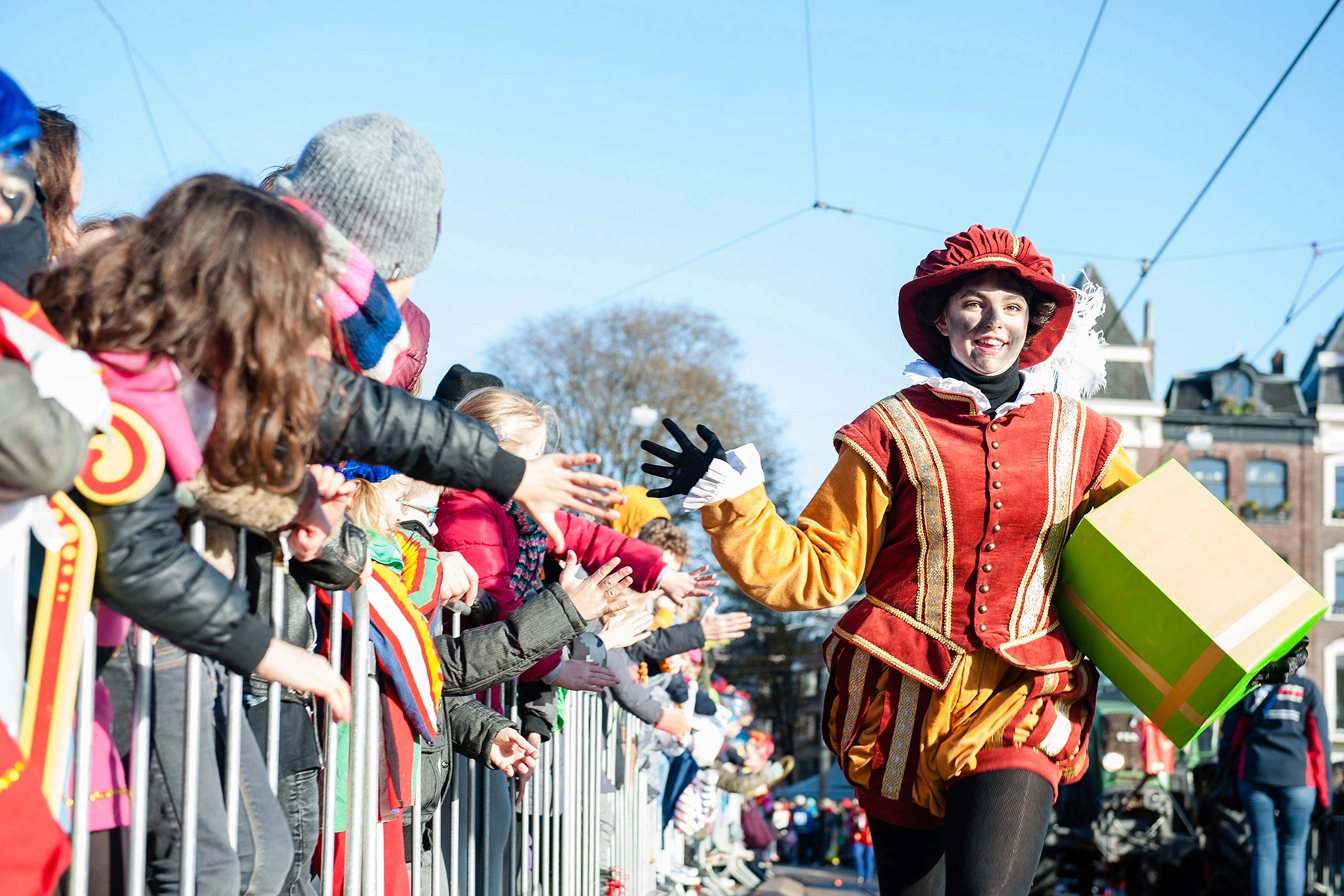Sooty Pete is giving high fives to a bunch of kids who are waiting for Sinterklaas to arrive in Amsterdam