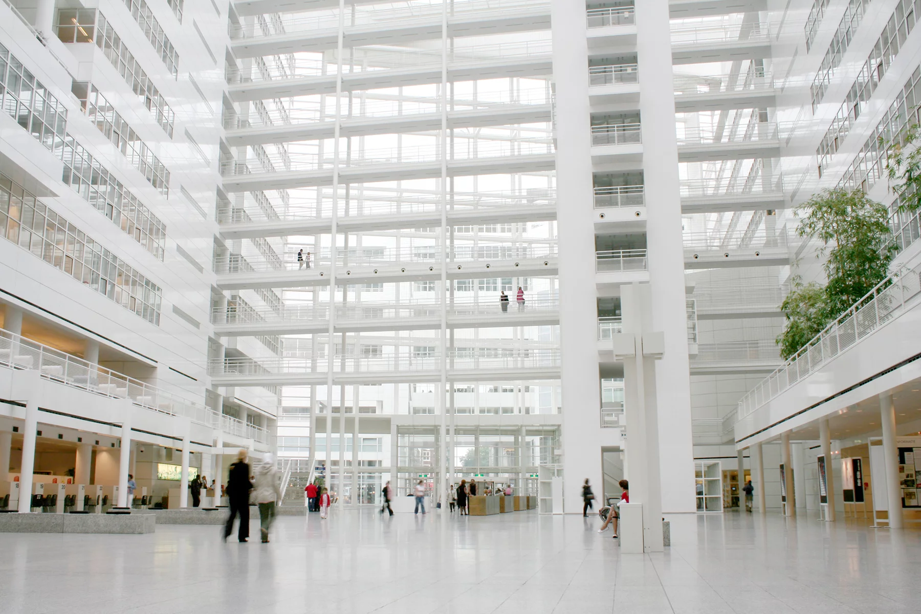 The interior of a large public atrium showing several floors, white railings
