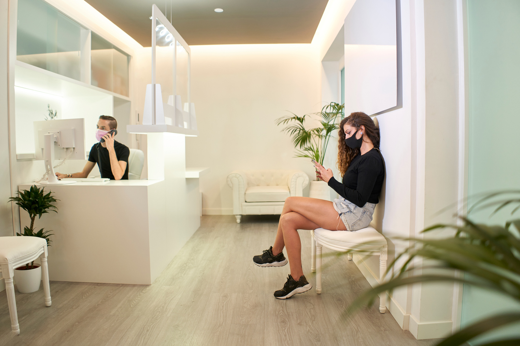 a young woman waiting in a dental practice wearing a face mask