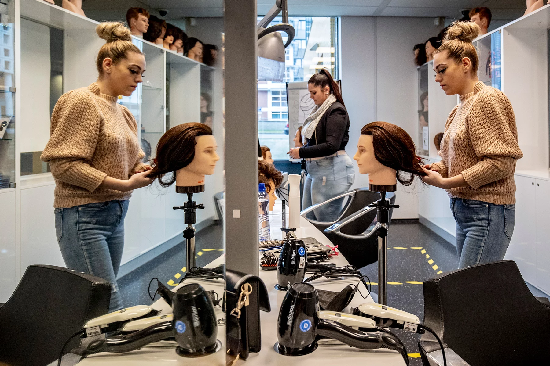Students in hairdresser training working on a dummy head with hair