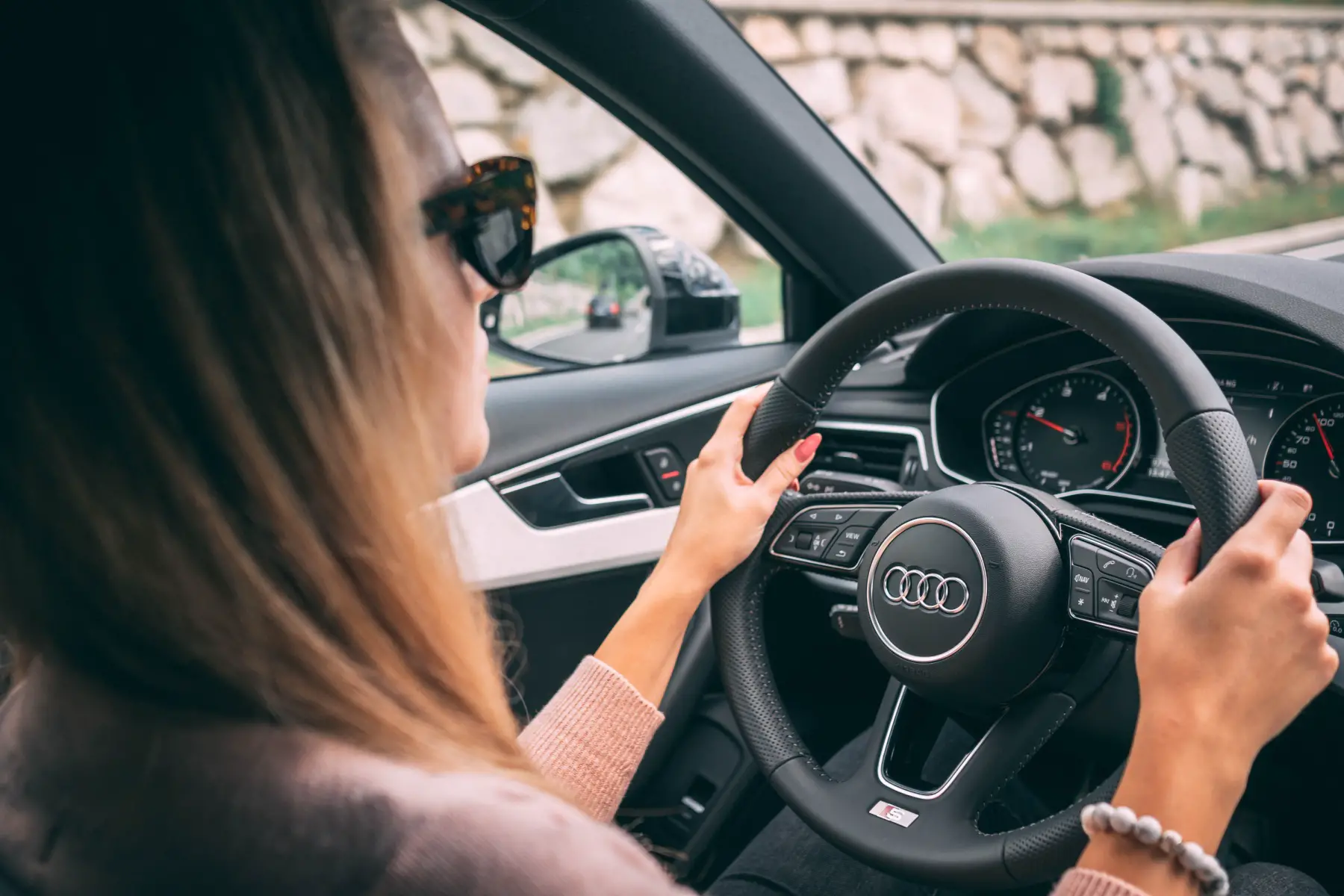 a stylish woman wearing shades and test-driving an Audi car