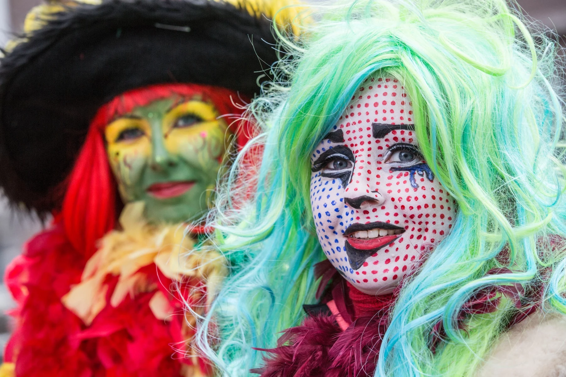 Two women in colorful face paint and wigs