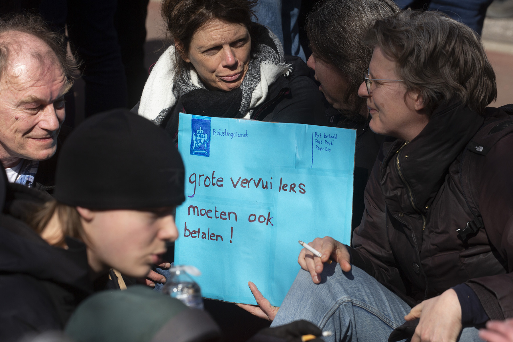 Protesters hold a sign in the form of a blue envelope saying "big polluters have to pay tax too" during an Extinction Rebellion protest against fossil fuel subsidies. The blue envelop is a symbol for the Dutch Tax Office, which always sends (or used to send) their post in blue envelops.