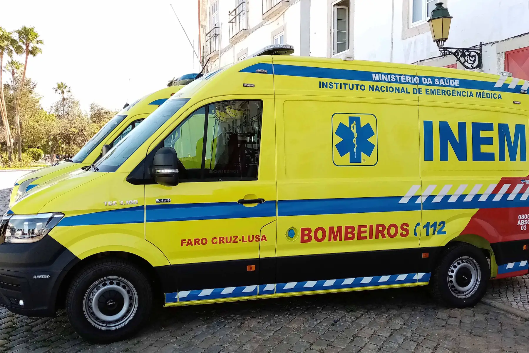 Two Portuguese ambulances marked with the emergency number and Ministério Da Saúde are parked on a street in Faro, Algarve