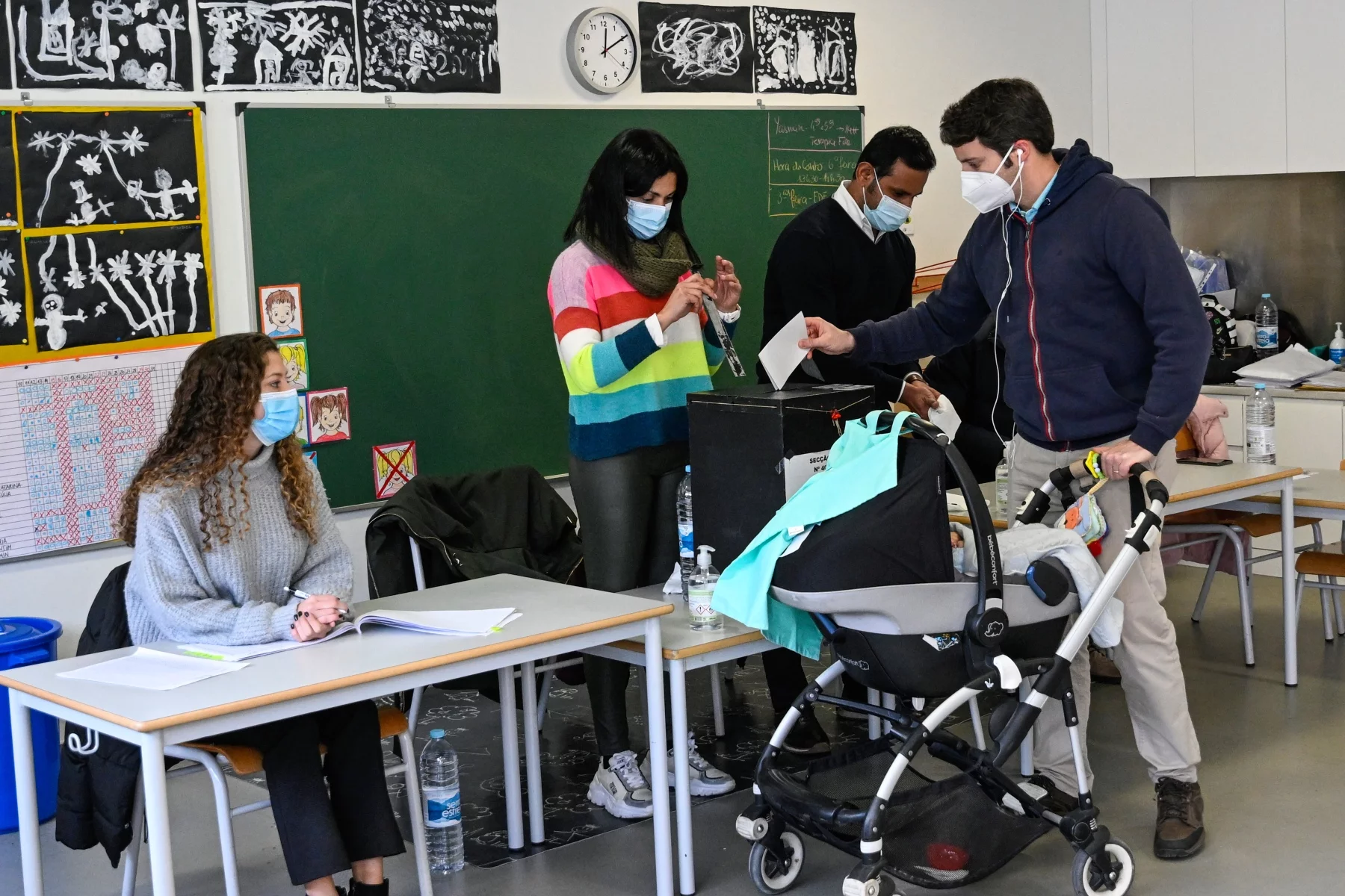 A man with a pram puts a ballot into a ballot box in a polling station in Lisbon