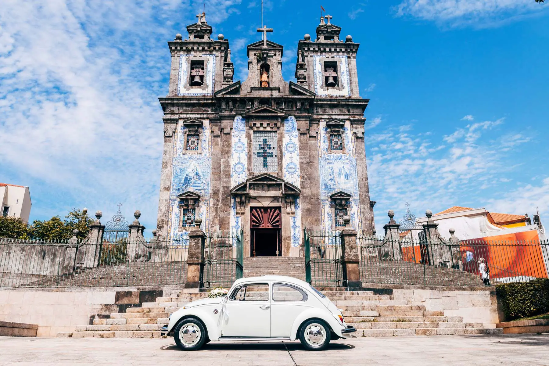 an old VW Beetle parked outside an old church in Portugal