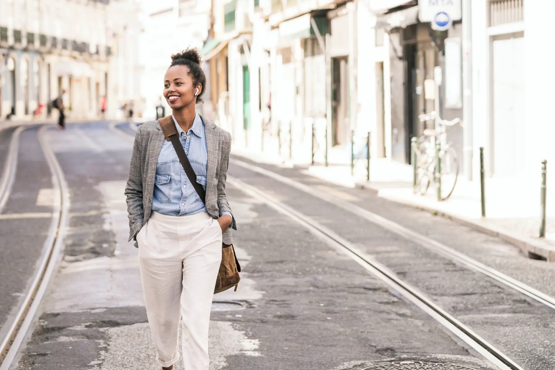 a smartly dressed woman walking down a street in Lisbon 