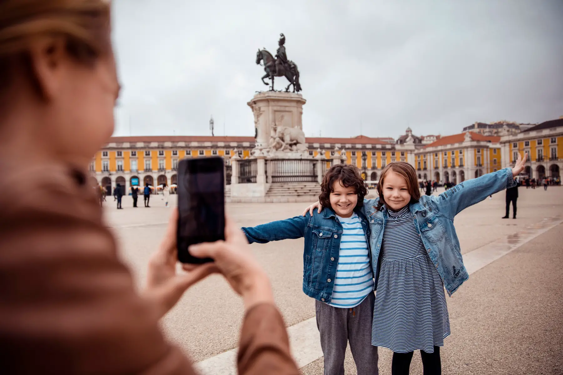 Two smiling children having their photo taken outside Praça do Comércio in Portugal's capital, Lisbon