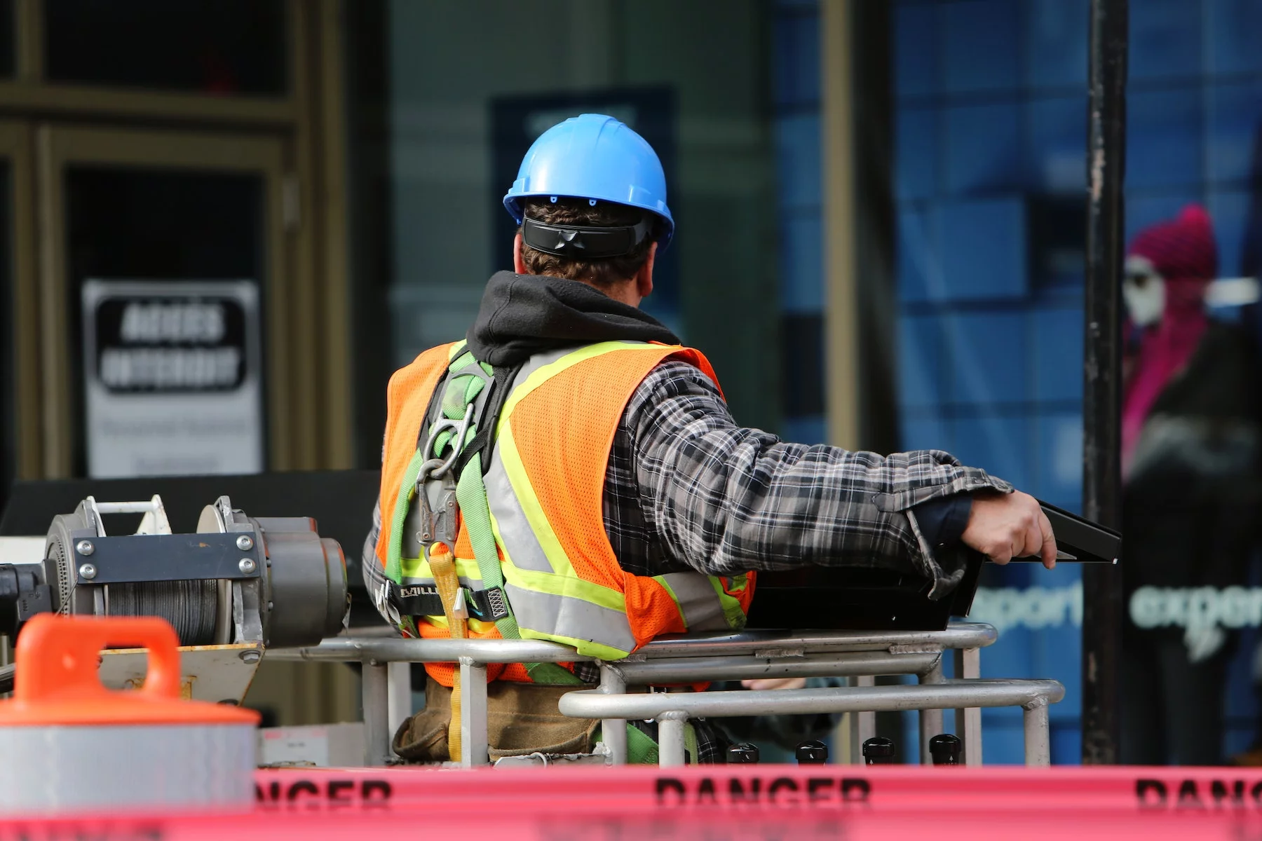 a construction worker in a hard hat and safety vest has his back toward the camera