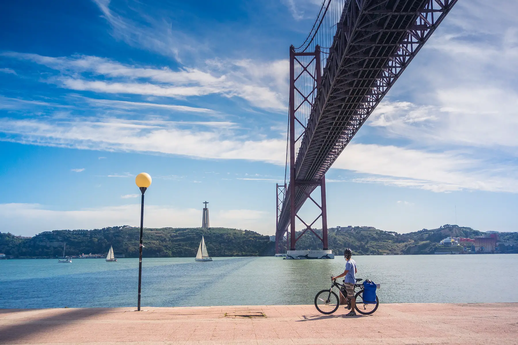 Cyclist under the Ponte 25 de Abril in Lisbon, Portugal