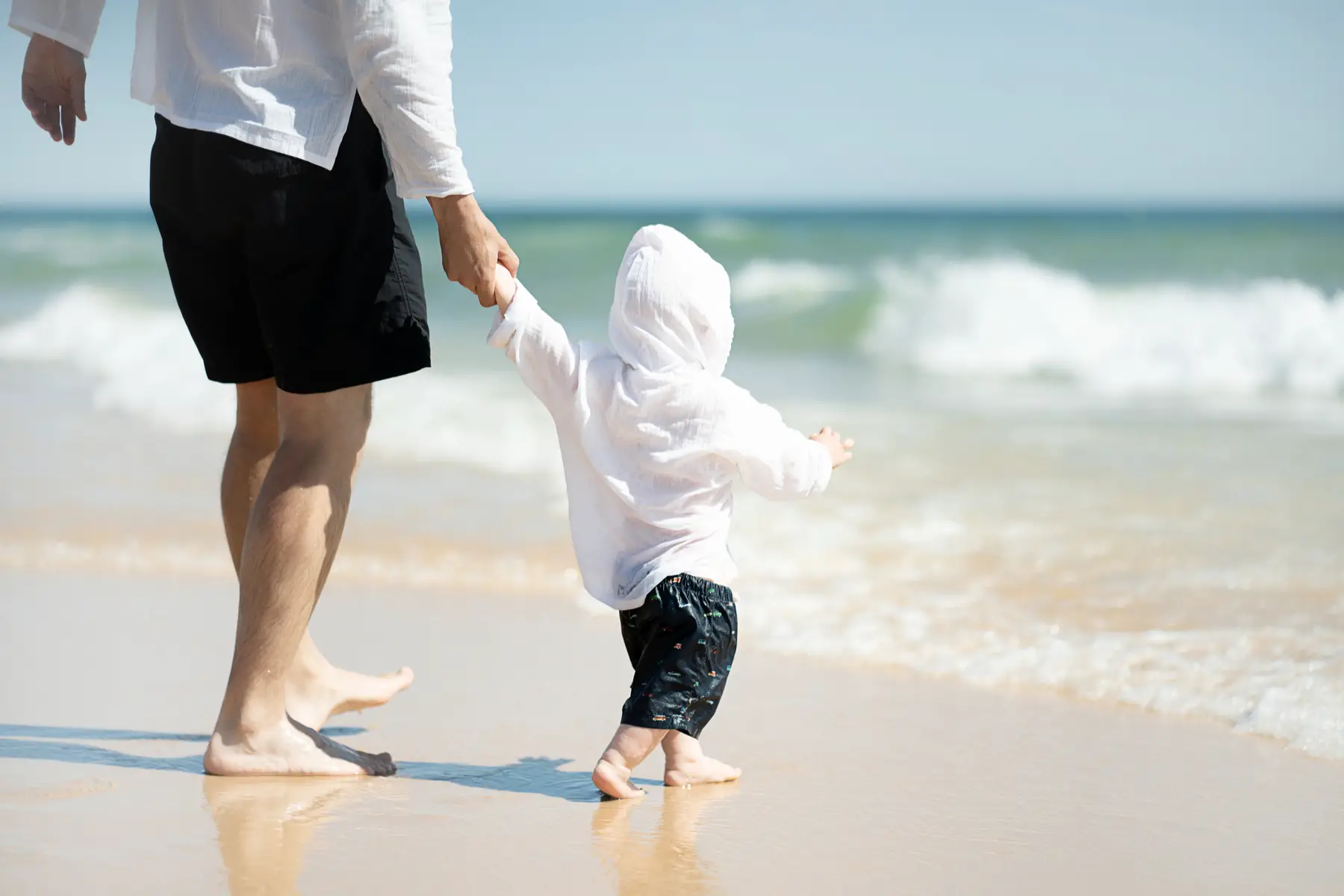 Father holding his son's hand at the beach