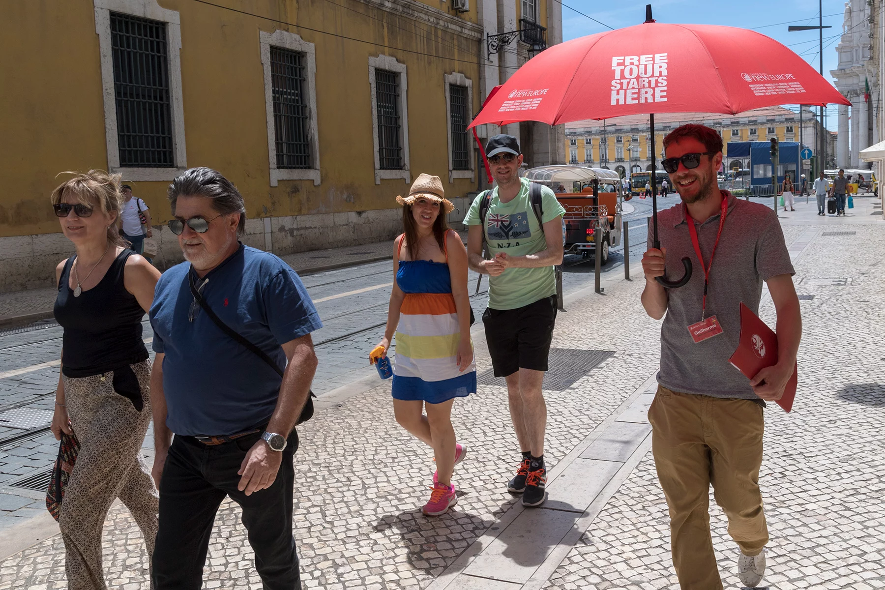 A tour guide walks with four tourists in Lisbon