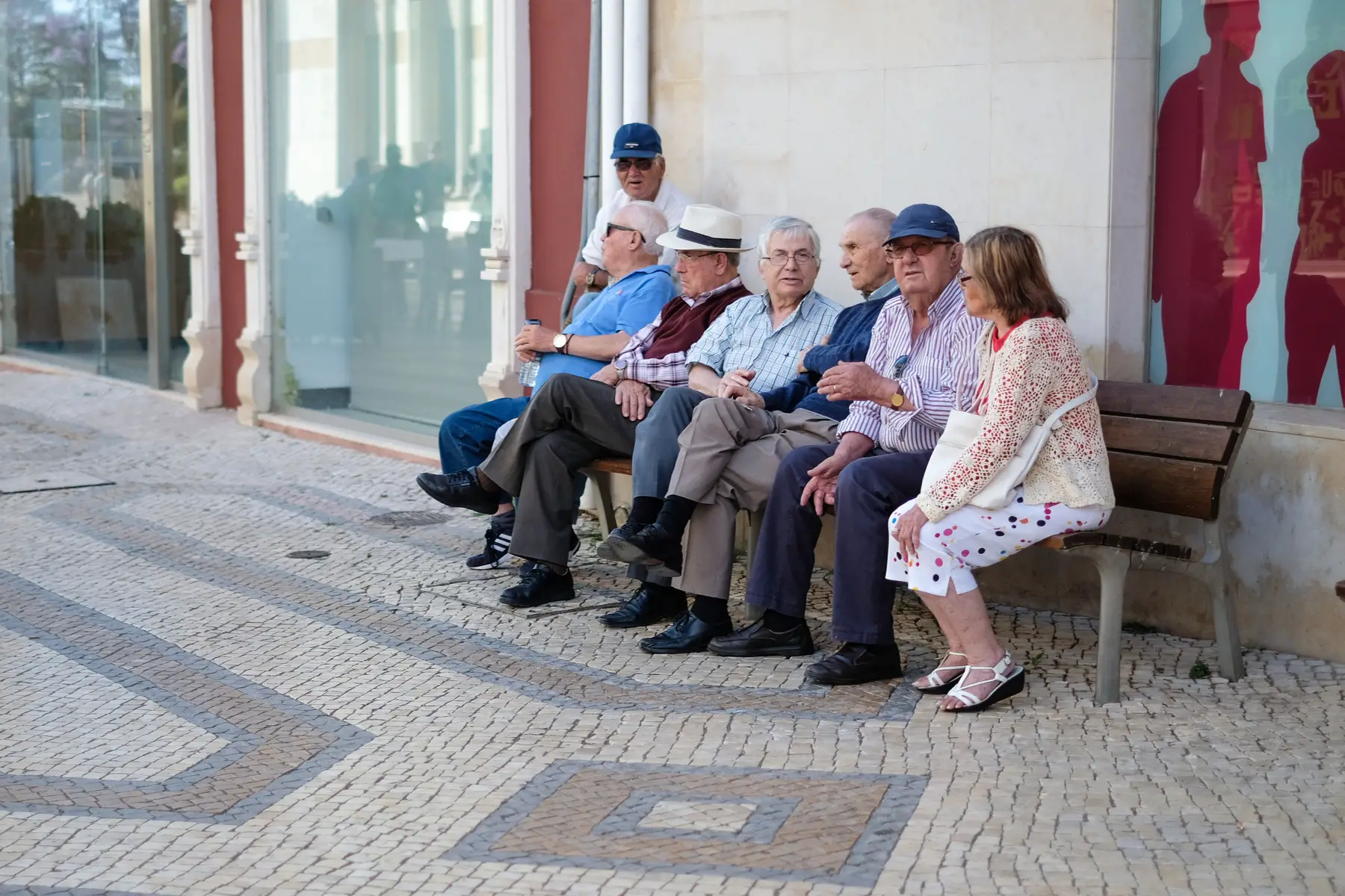 a group of pensioners relaxing on a bench in the center of Faro in Portugal