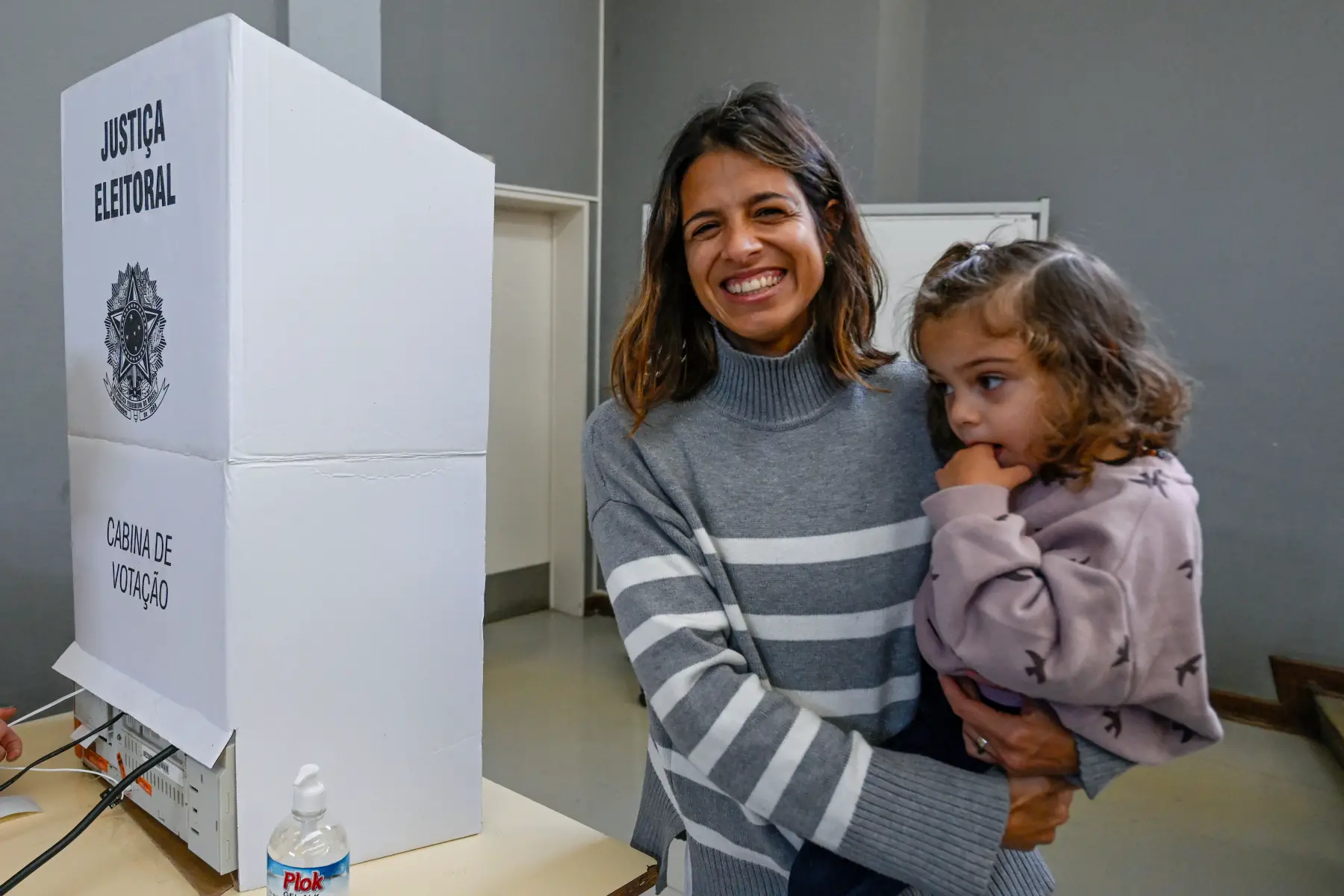 Brazilian mother holds child next to voting booth after voting in Presidential Election