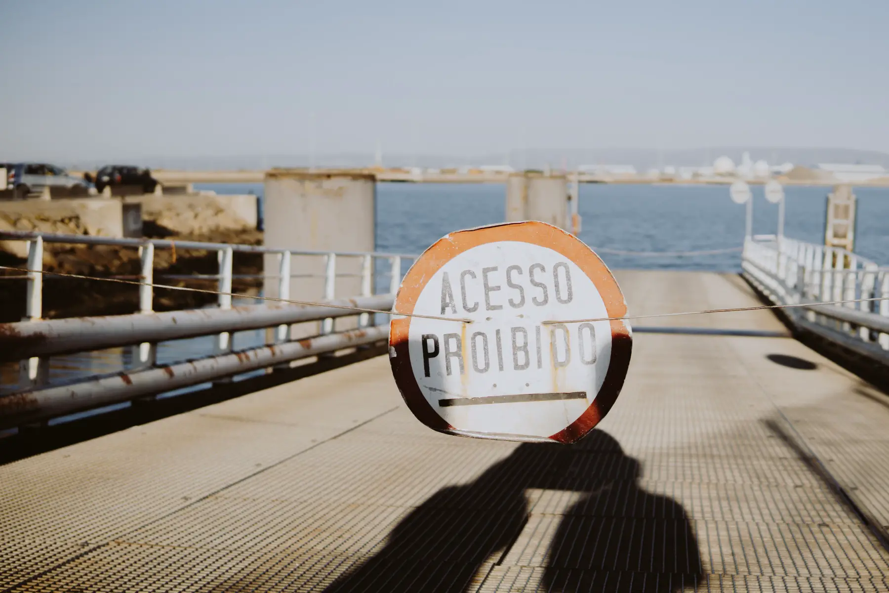 A faded Portuguese sign on a pier in Aveiro, Portugal that says 'Acesso Proibioo' (prohibited access)