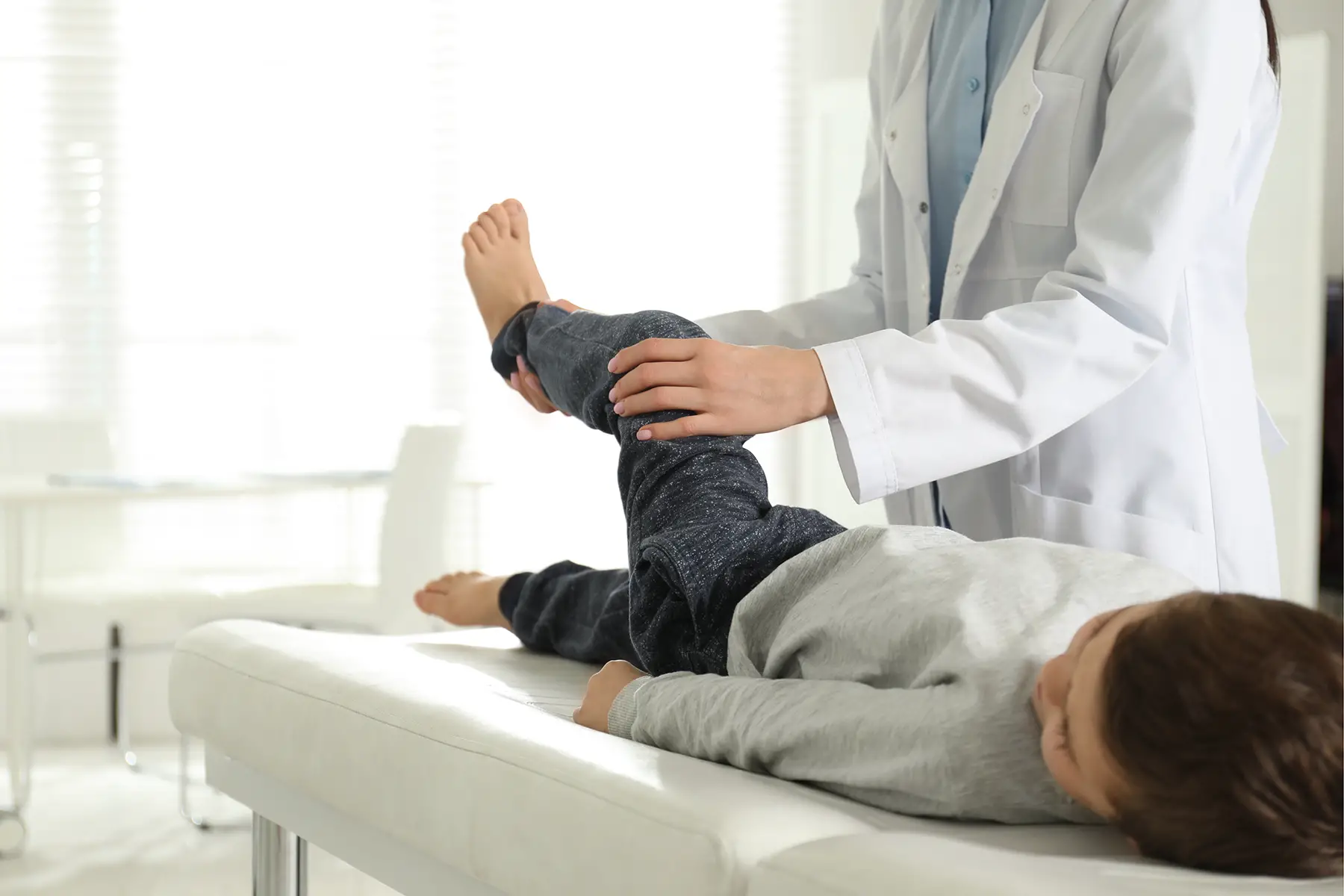 an orthopedist examining a child's leg in a clinic