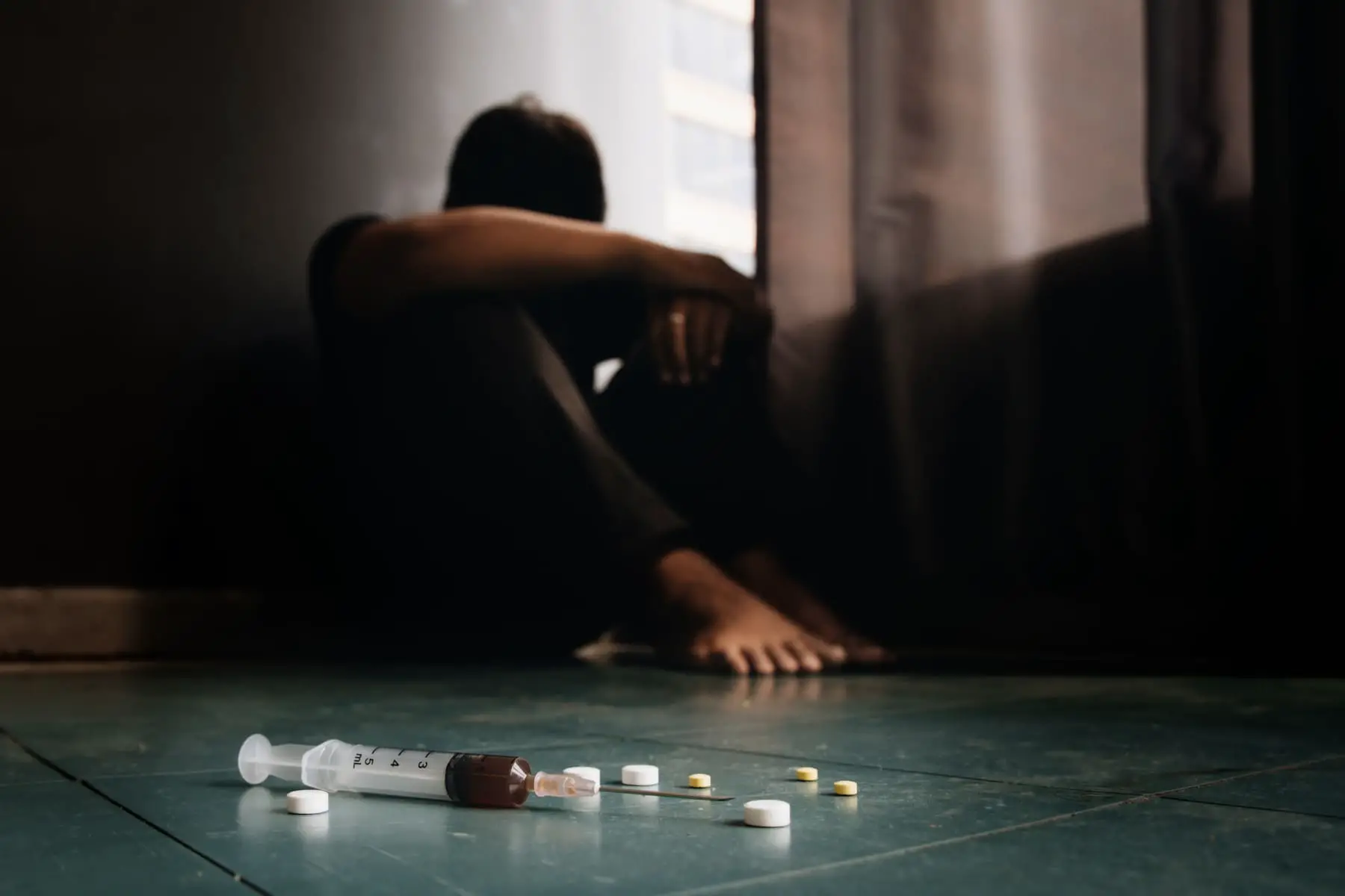 a person holding their knees while struggling with drug addiction