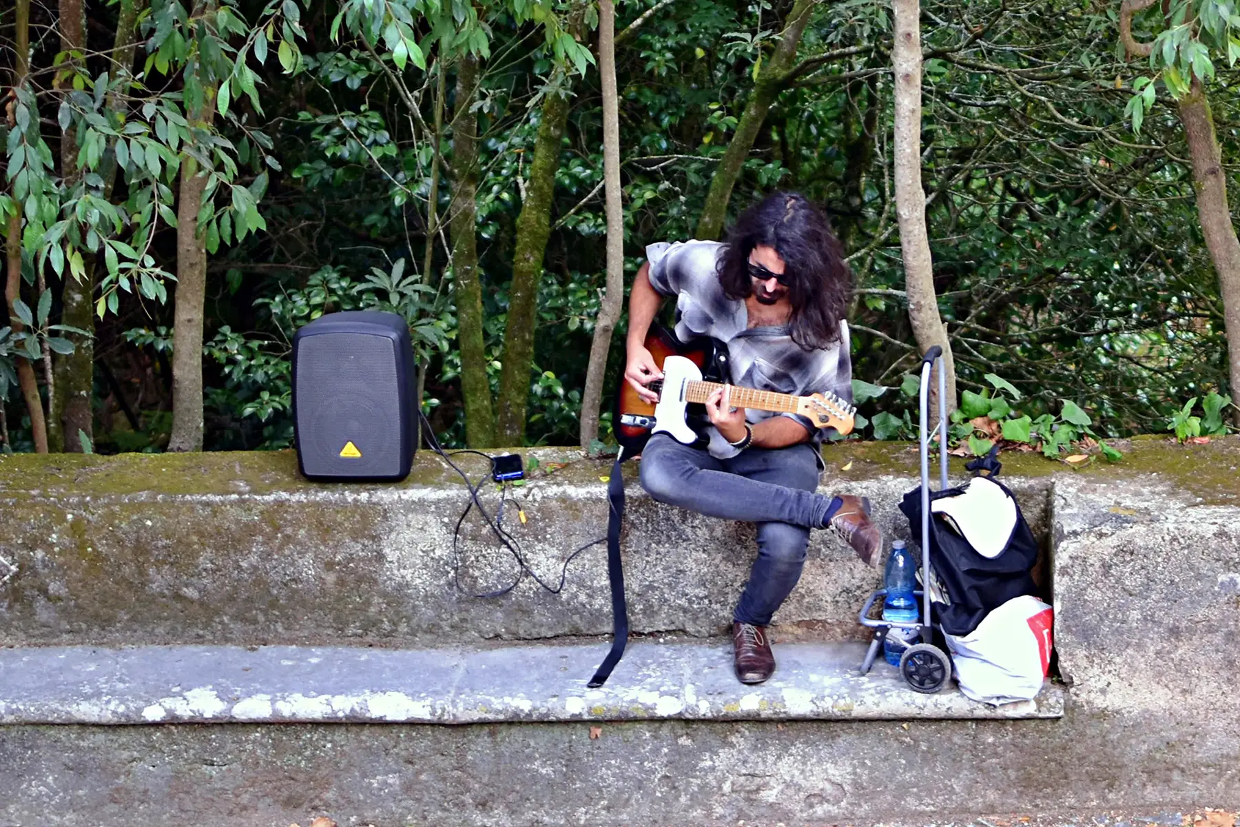 A street musician playing electric guitar with an amplifier