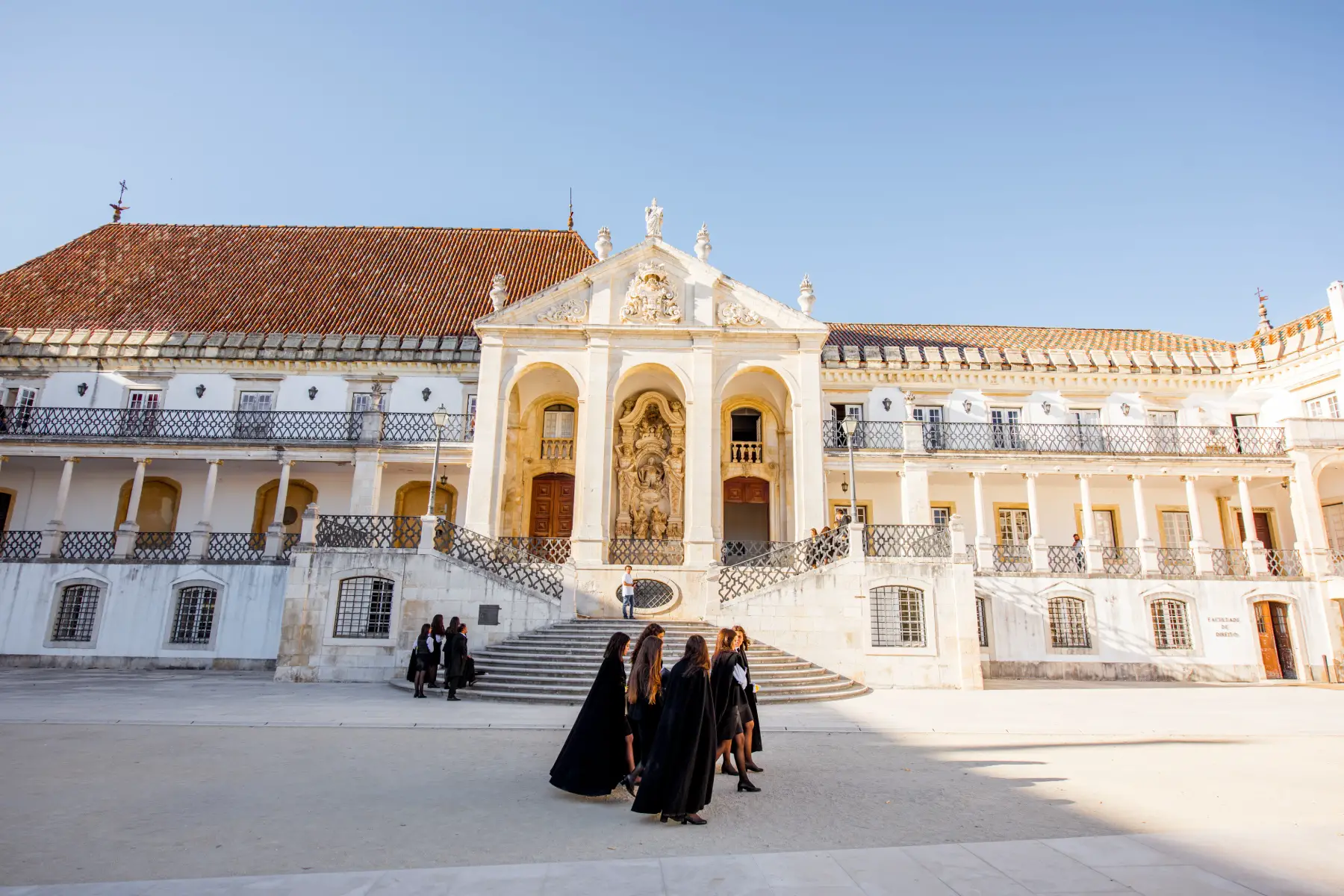 Students walk through Coimbra University wearing traditional gowns