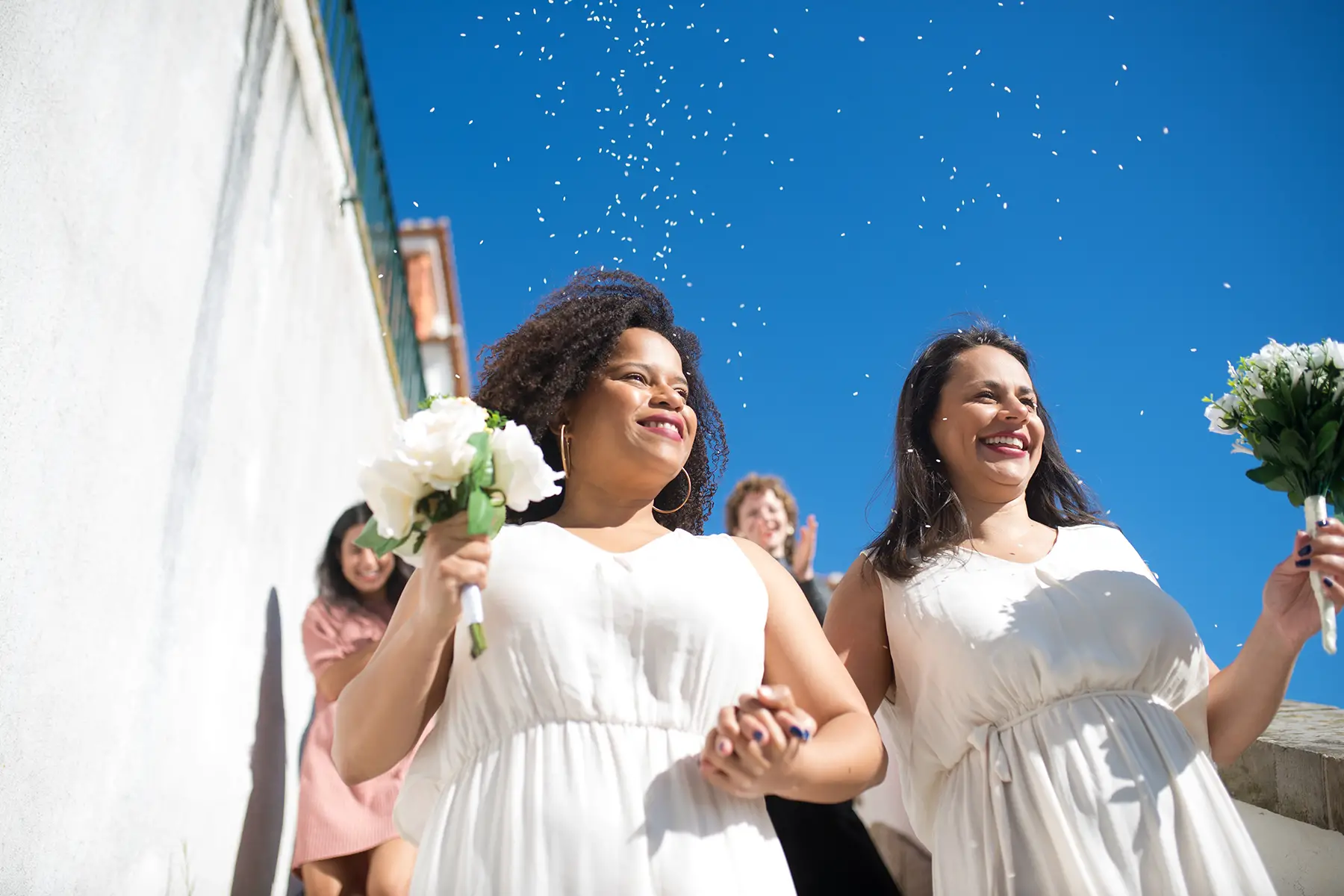 Wedding guests throwing rice over two brides in Portugal
