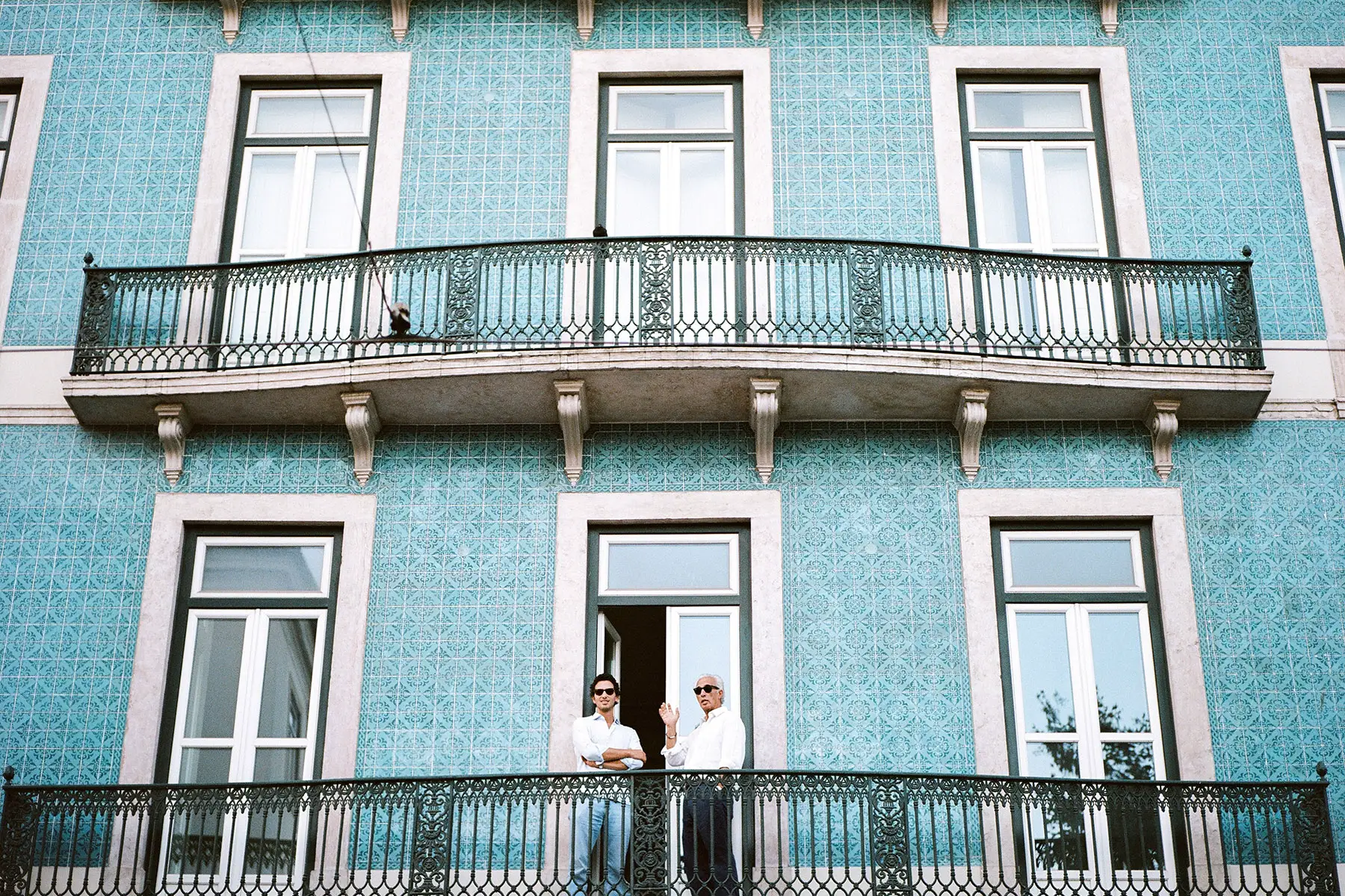Two men standing on a balcony of a Portuguese house