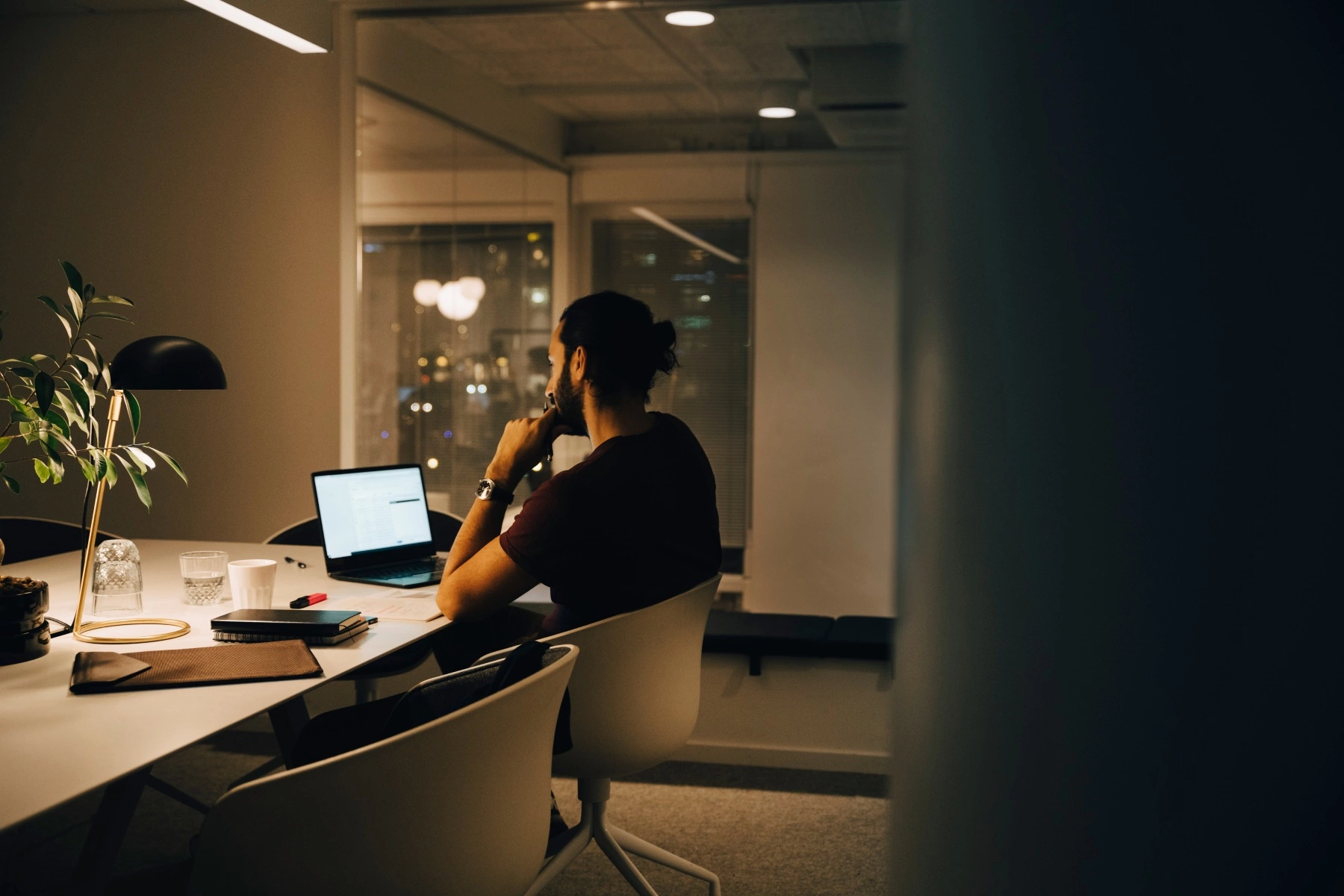 a male employee working late at an illuminated desk in a co-working space