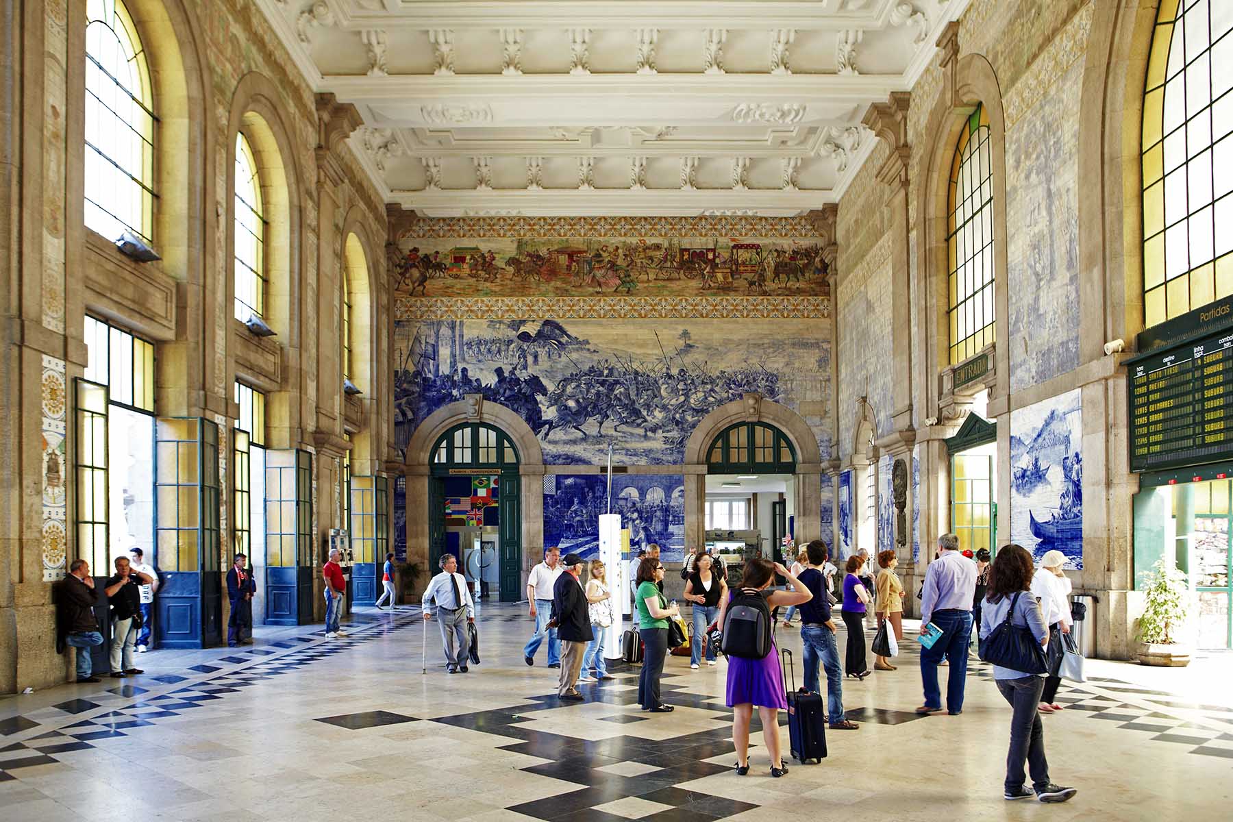 People waiting Sao Bento train station in Central Porto, Portugal. The historical station features the iconic blue tile panels that depict scenes of the history of Portugal.