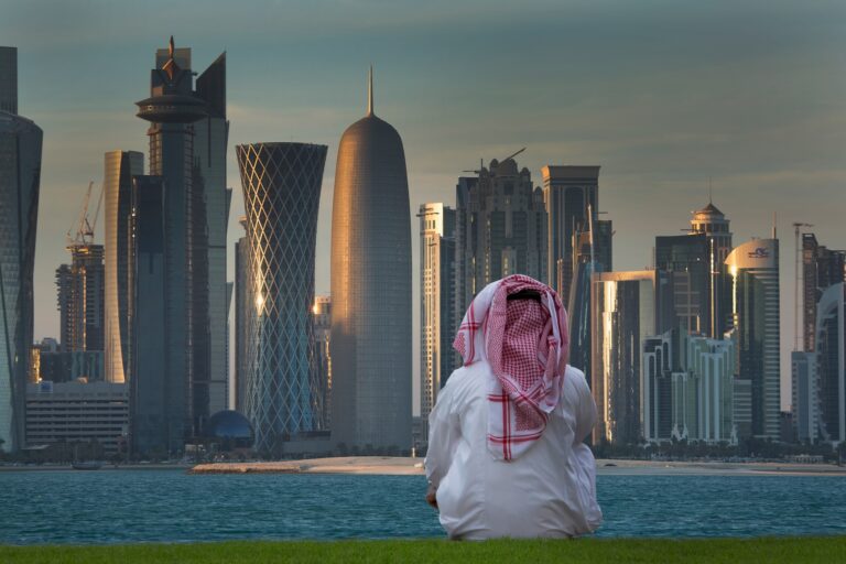 A man in traditional attire looks out over the Doha skyline in Qatar