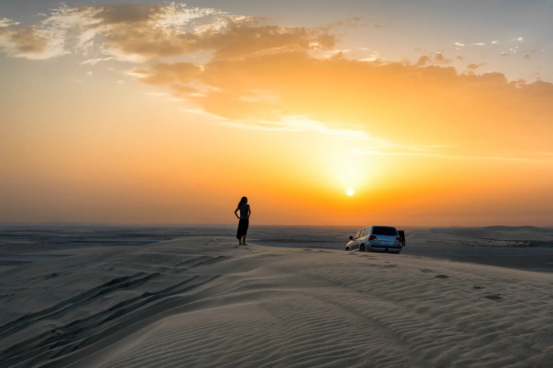 Driving through sand dunes in Qatar at sunset