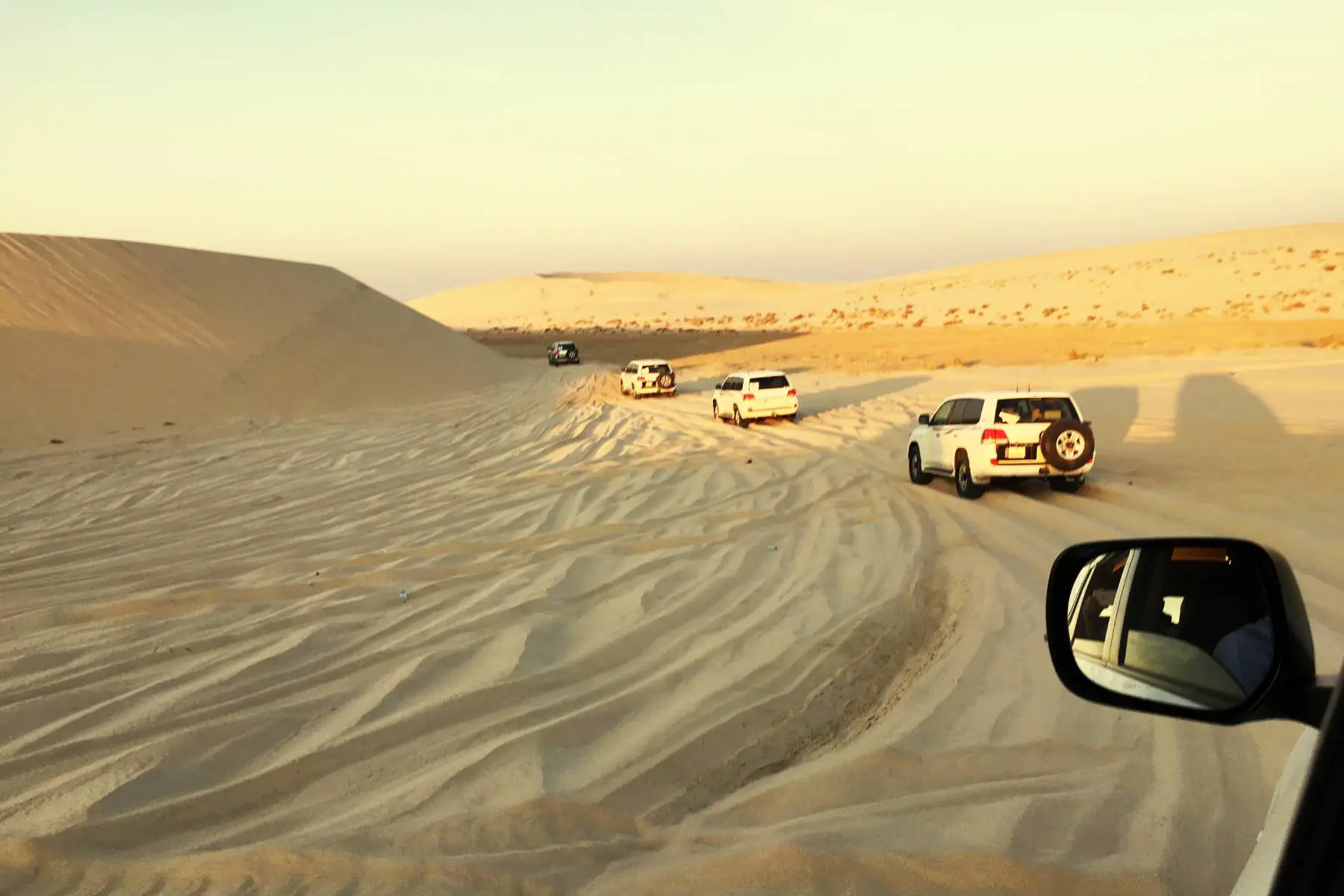 Cars driving in a line through the Ash Shaqra' desert in Qatar.