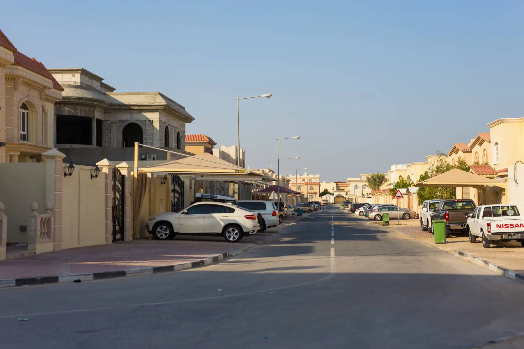 Cars and trash cans outside homes on Al Jebailat residential area in Doha, Qatar.