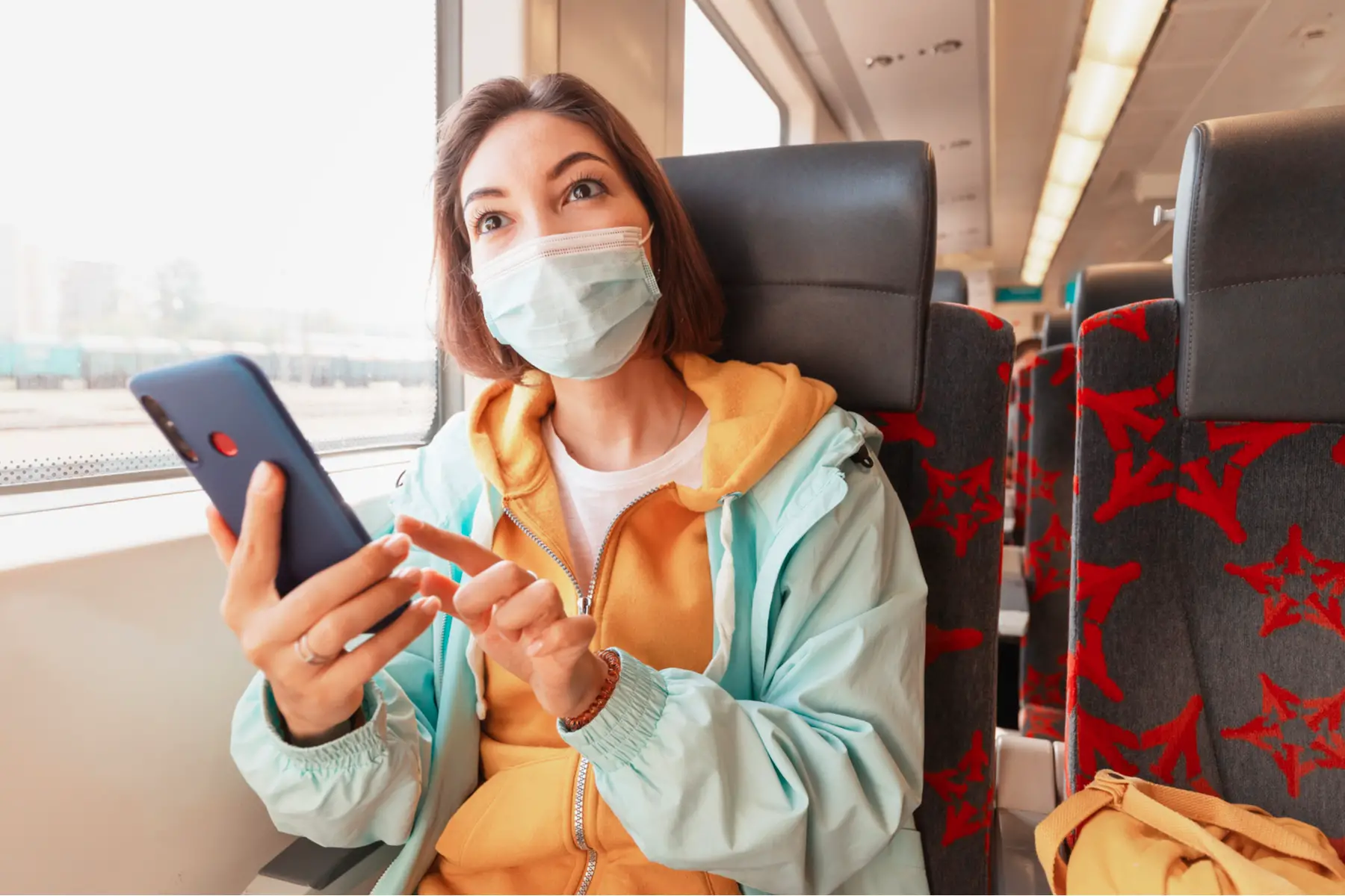 Woman wearing a mask while using her phone on a train