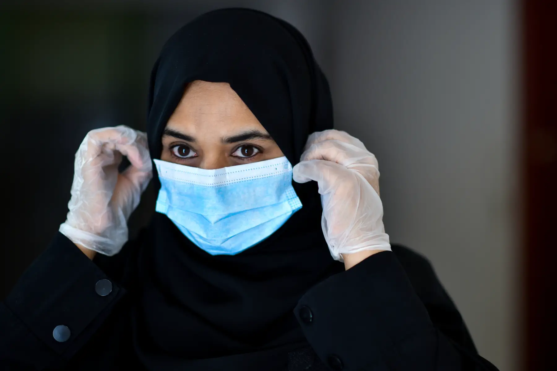 an Arab woman putting on a face mask during the coronavirus pandemic in Saudi Arabia
